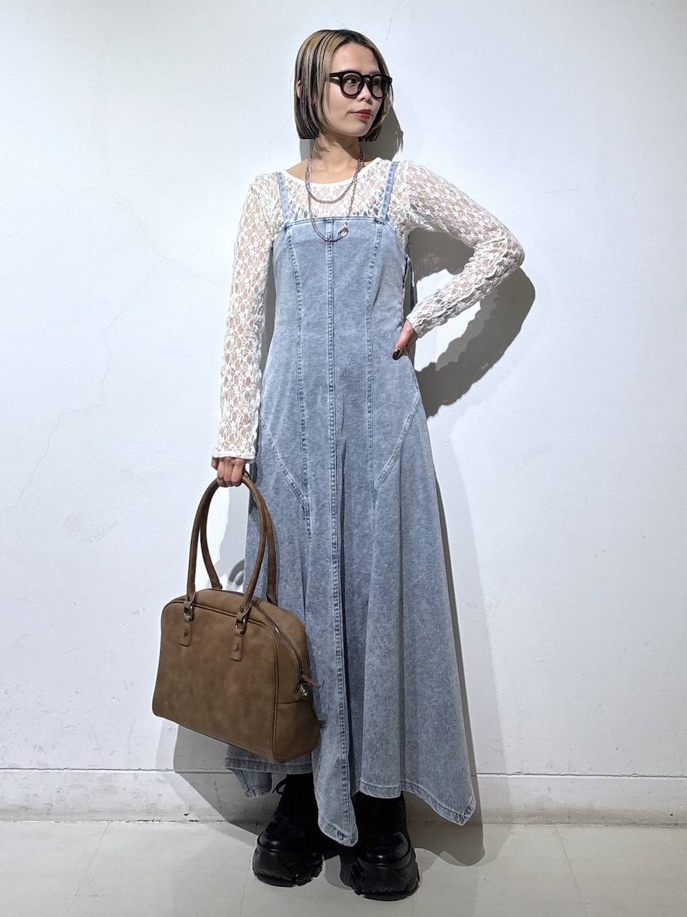 ブラック系のブーツ、ベージュ系のボストンバッグ、ブルー系のワンピースを着用したレディースの冬コーディネートの1枚目の写真