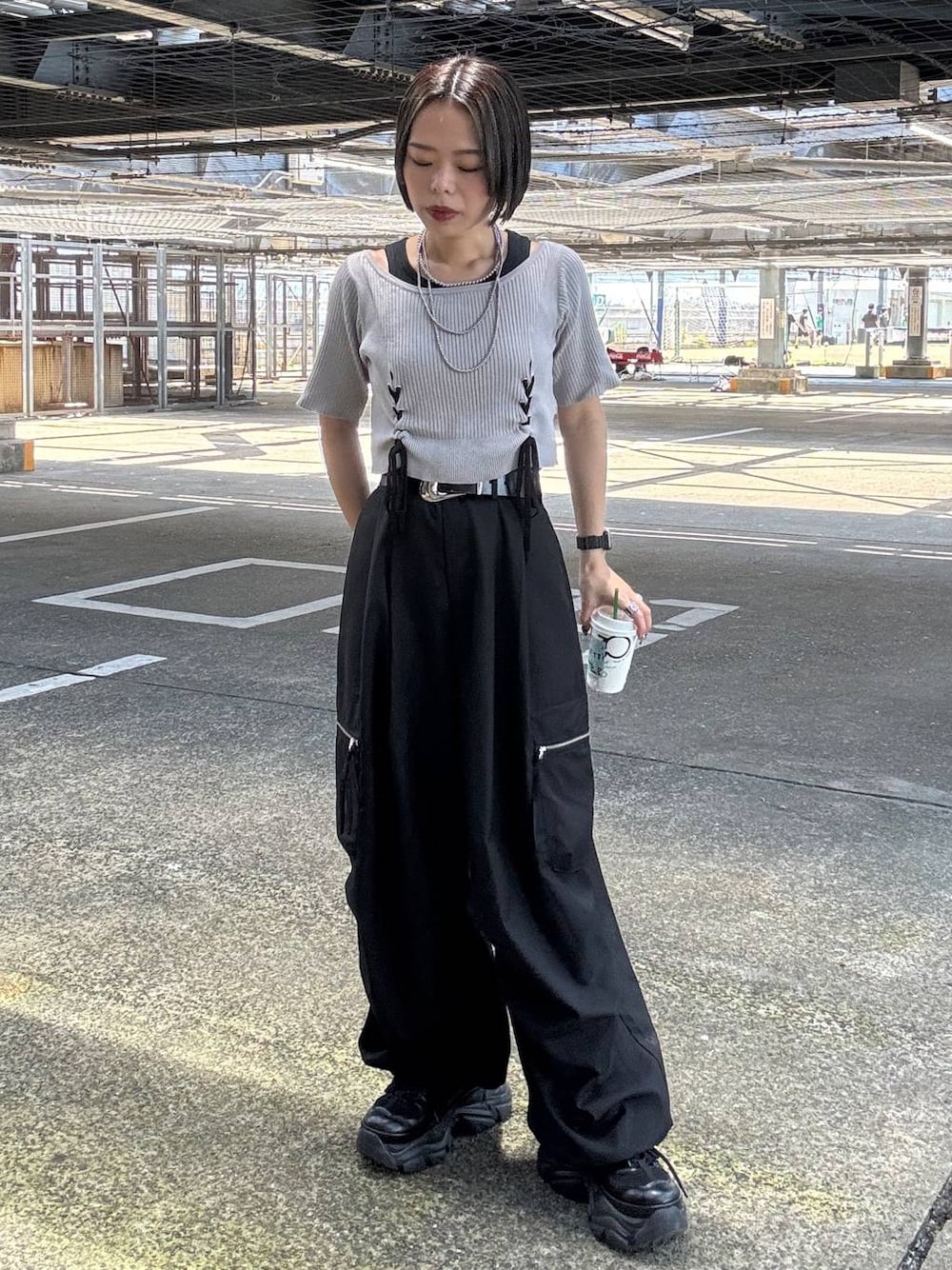 ブラック系のカーゴパンツ、グレー系のTシャツ/カットソー、ブラック系のスニーカーを着用したレディースの夏コーディネートの1枚目の写真