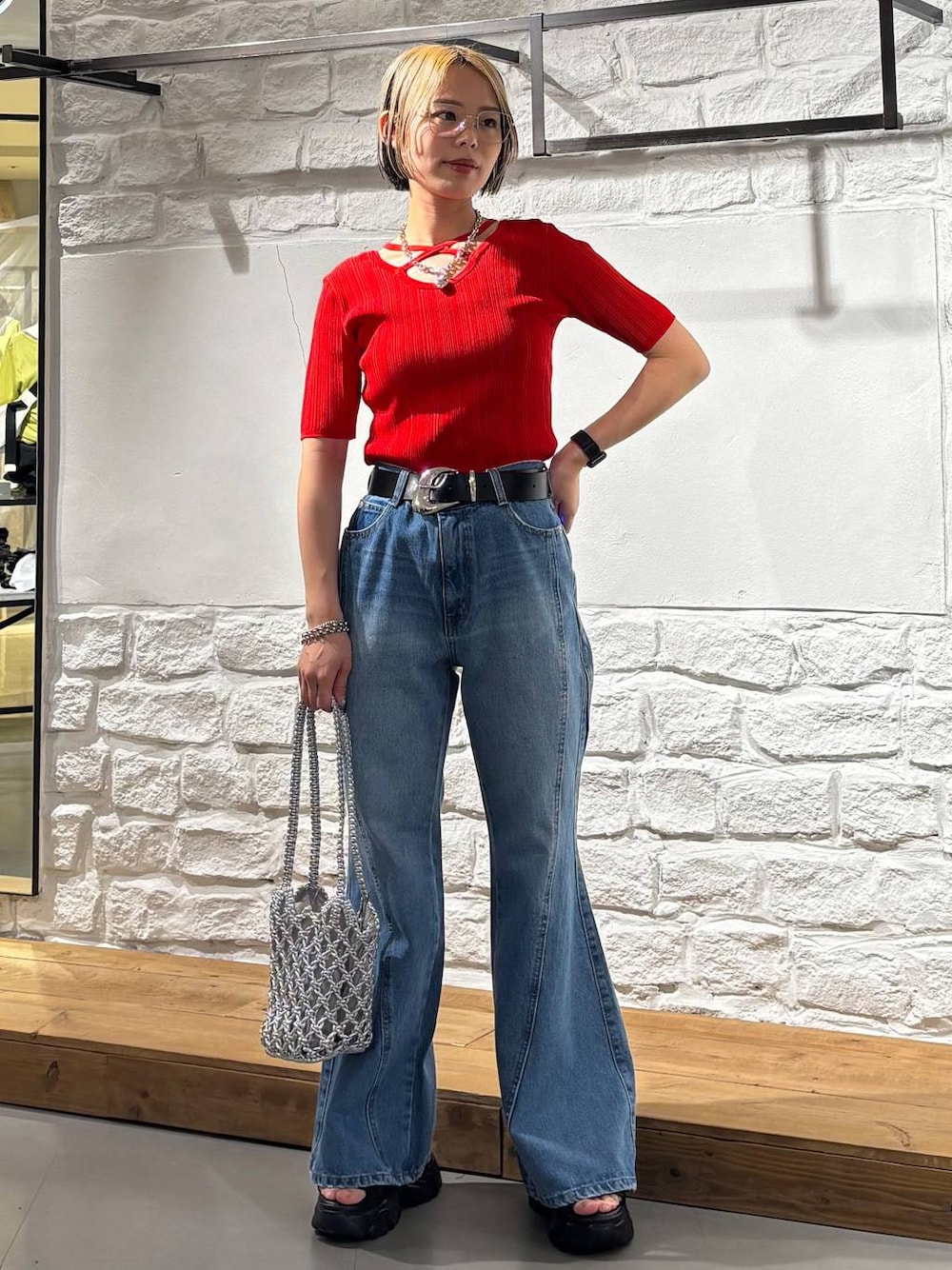 ブルー系のデニムパンツ、ブラック系のサンダル、レッド系のニット/セーターを着用したレディースの春コーディネートの1枚目の写真