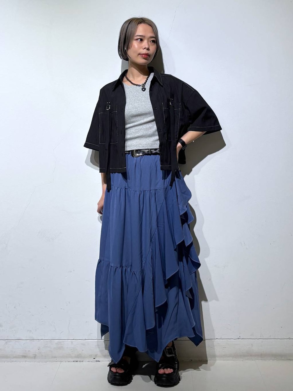 ブルー系のスカート、グレー系のTシャツ/カットソー、ブラック系のサンダルを着用したレディースの春コーディネートの1枚目の写真