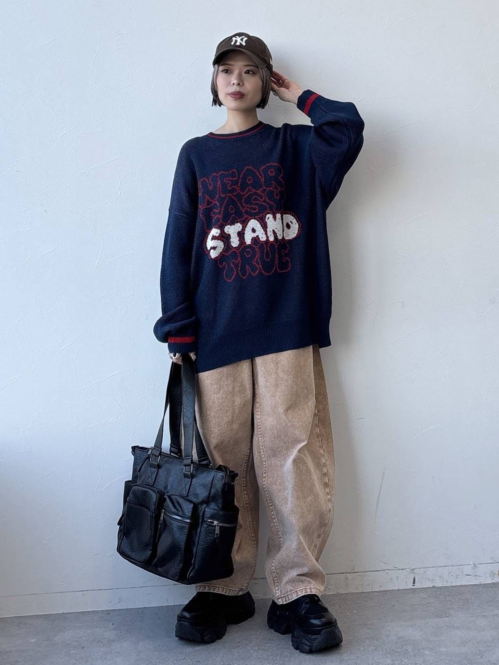 ブラック系のスニーカー、ブラック系のボストンバッグ、ブラウン系のデニムパンツを着用したレディースの冬コーディネートの1枚目の写真