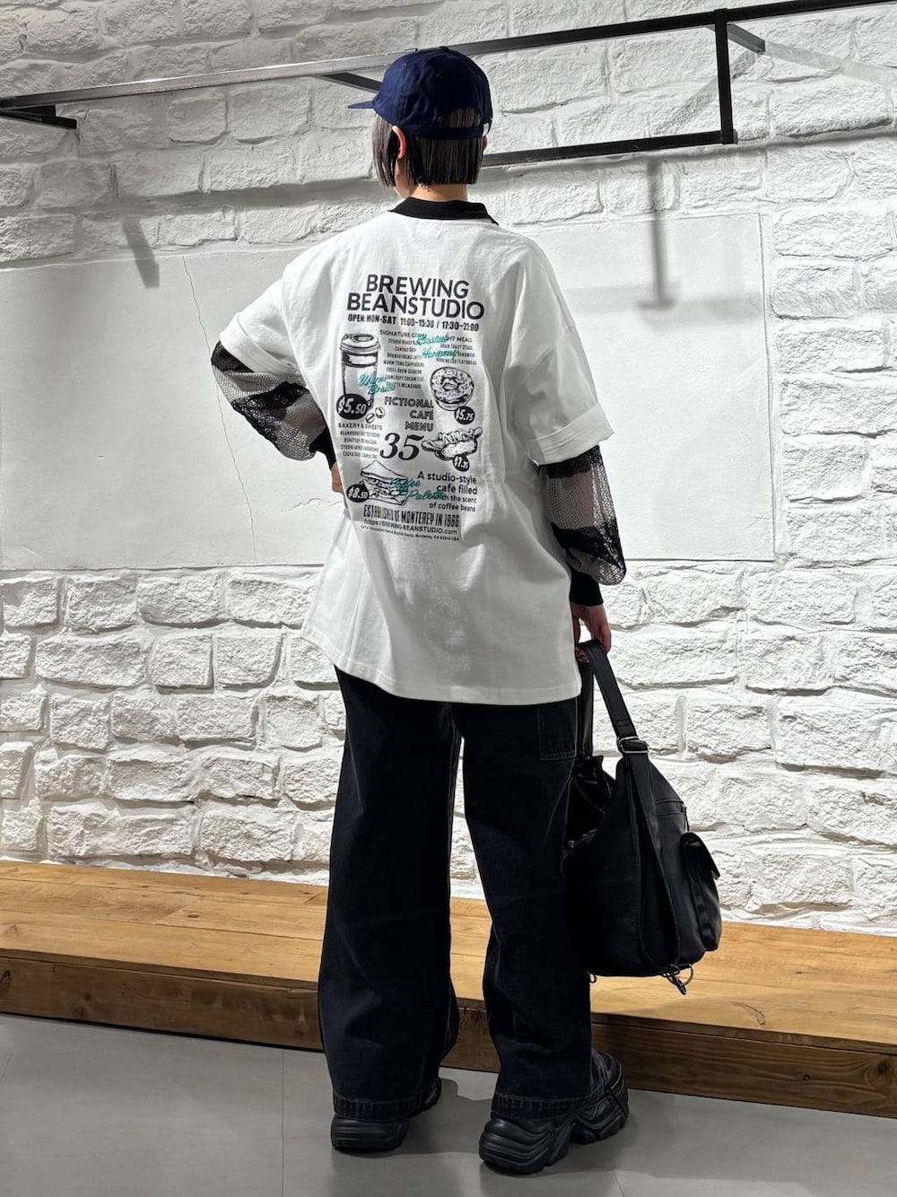 ブラック系のスニーカー、ブラック系のショルダーバッグ、ブラック系のデニムパンツを着用したレディースの春コーディネートの1枚目の写真