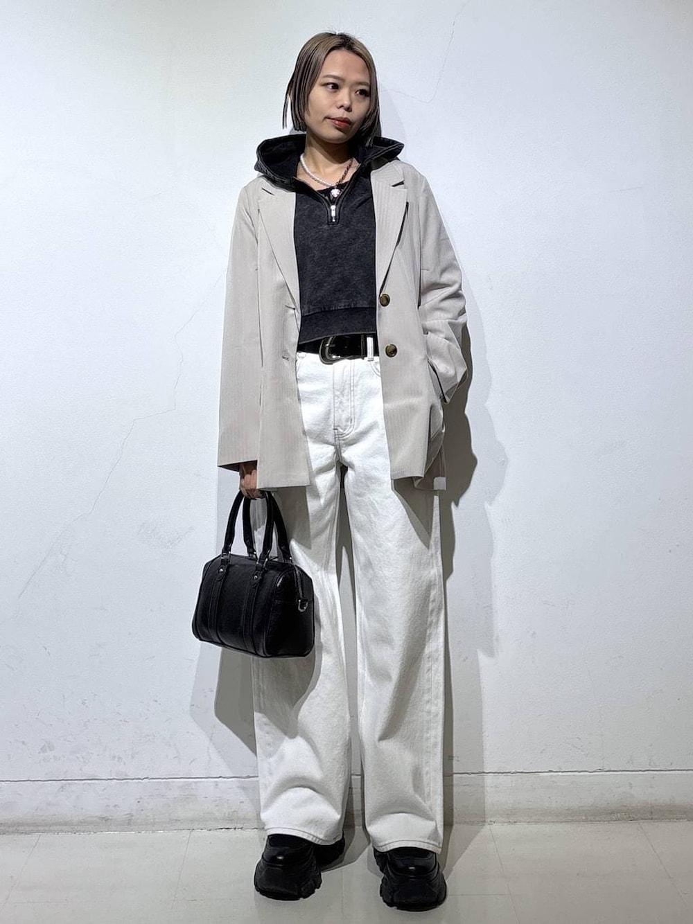 ブラック系のブーツ、ブラック系のTシャツ/カットソー、ホワイト系のスラックスを着用したレディースの冬コーディネートの1枚目の写真