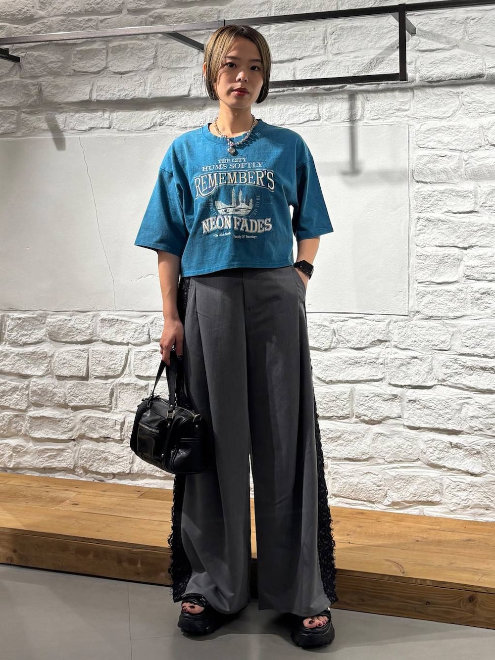 ブラック系のショルダーバッグ、ブルー系のTシャツ/カットソー、ブラック系のサンダルを着用したレディースの夏コーディネートの1枚目の写真