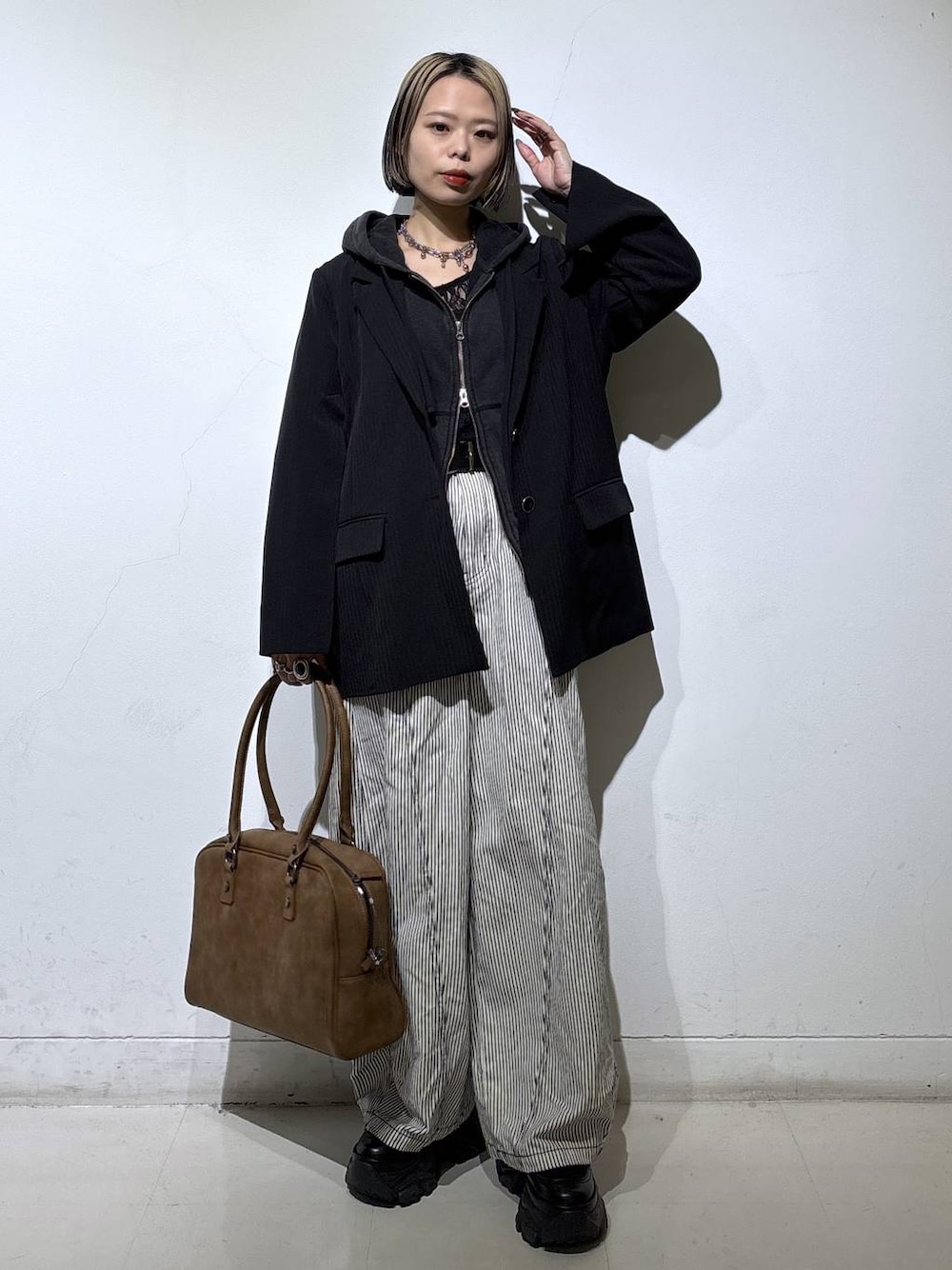 ブラック系のブーツ、ベージュ系のボストンバッグ、ブラック系のTシャツ/カットソーを着用したレディースの冬コーディネートの1枚目の写真