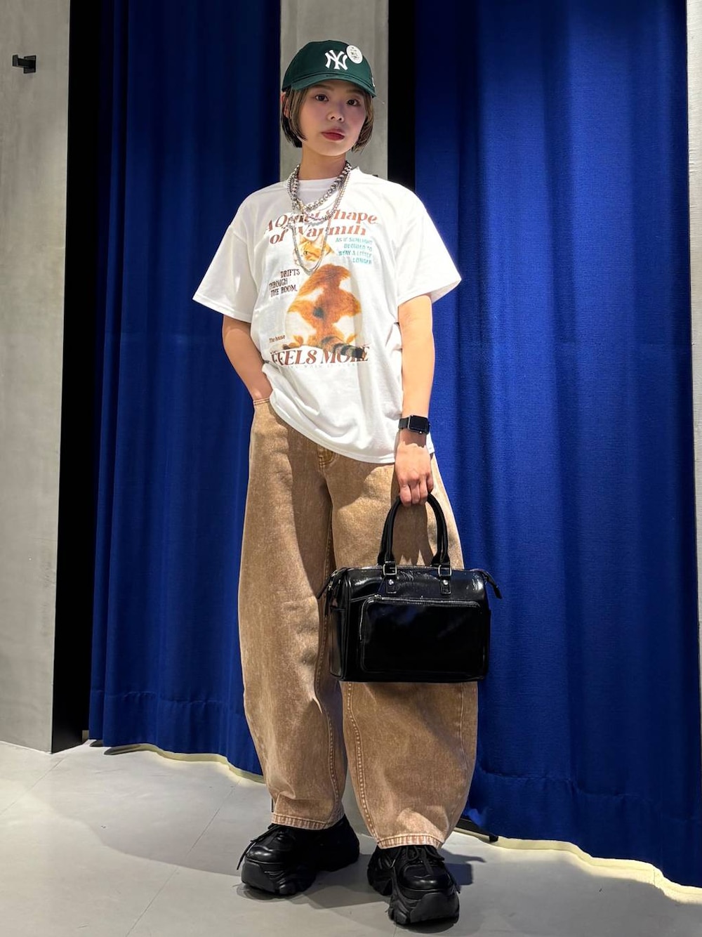 ブラック系のスニーカー、ブラウン系のデニムパンツ、ブラック系のショルダーバッグを着用したレディースの春コーディネートの1枚目の写真