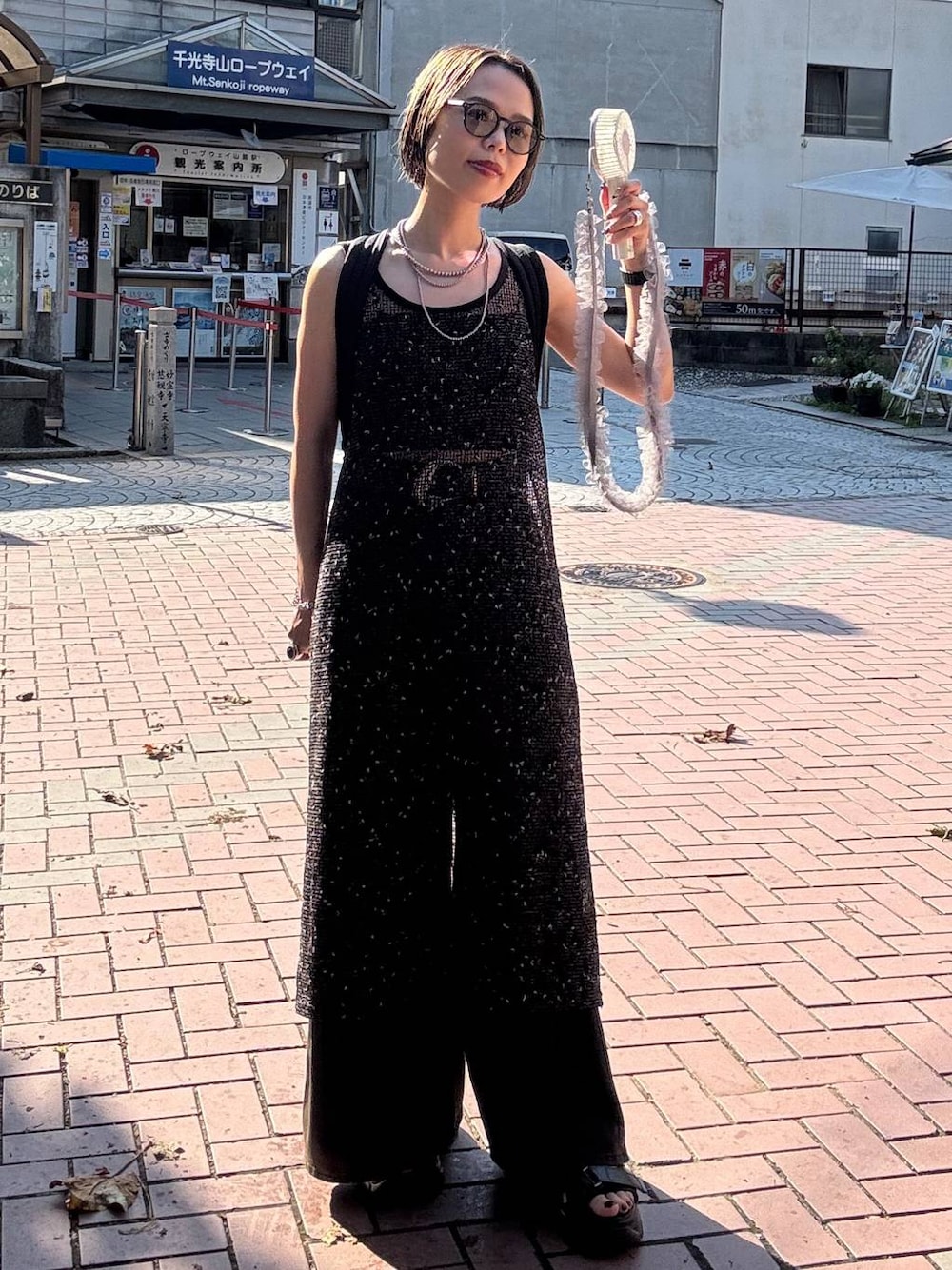 ブラウン系のデニムパンツ、ブラック系のサンダル、ブラック系のワンピースを着用したレディースの夏コーディネートの1枚目の写真