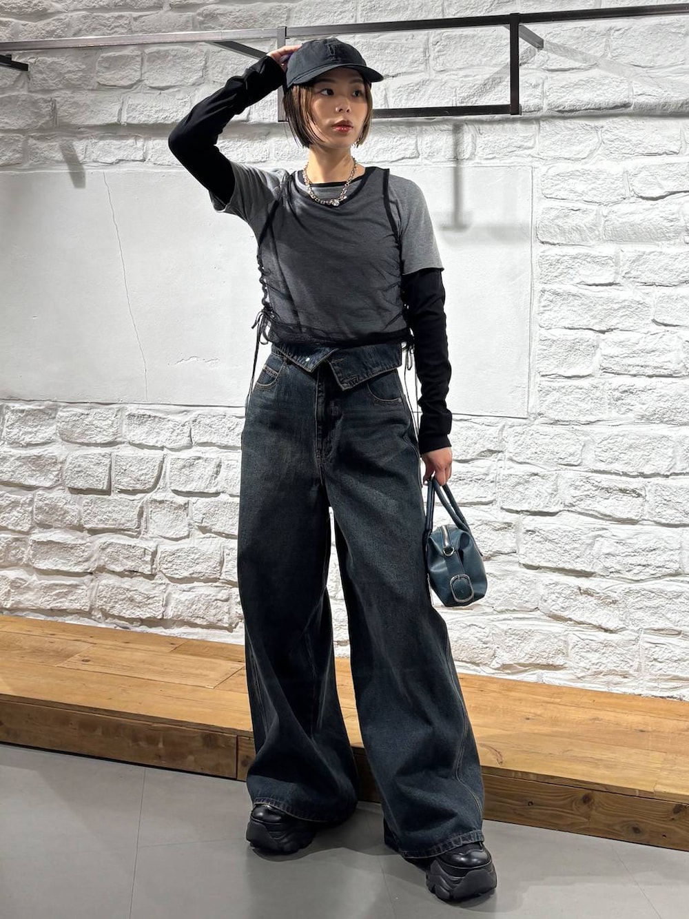 ブラック系のスニーカー、ブルー系のデニムパンツ、ブルー系のショルダーバッグを着用したレディースの秋コーディネートの1枚目の写真