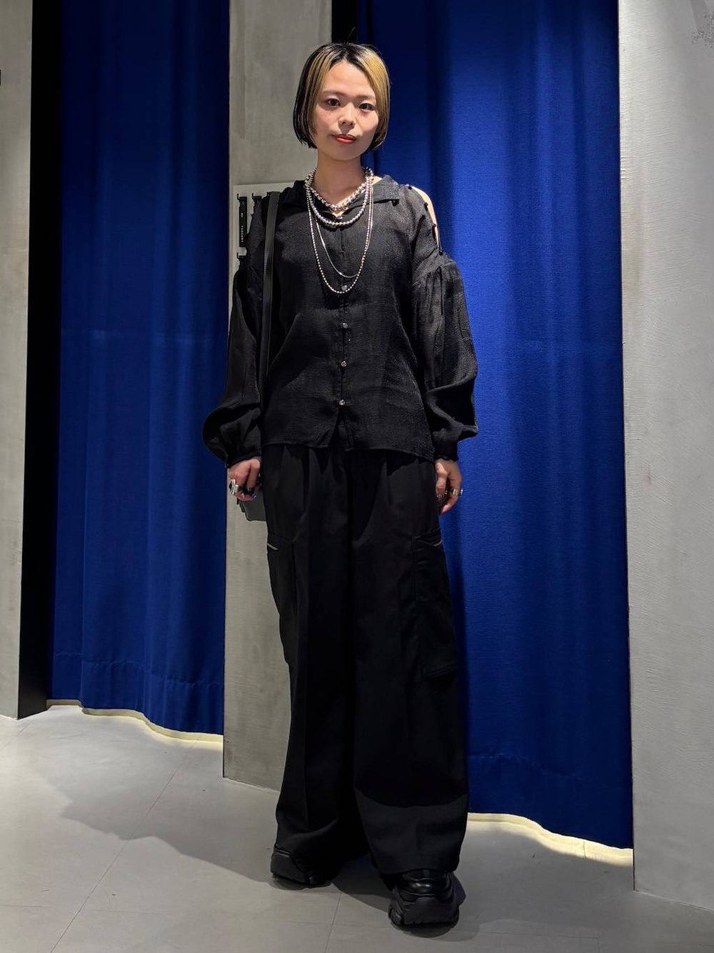 ブラック系のスニーカー、ブラック系のスラックス、グレー系のショルダーバッグを着用したレディースの春コーディネートの1枚目の写真