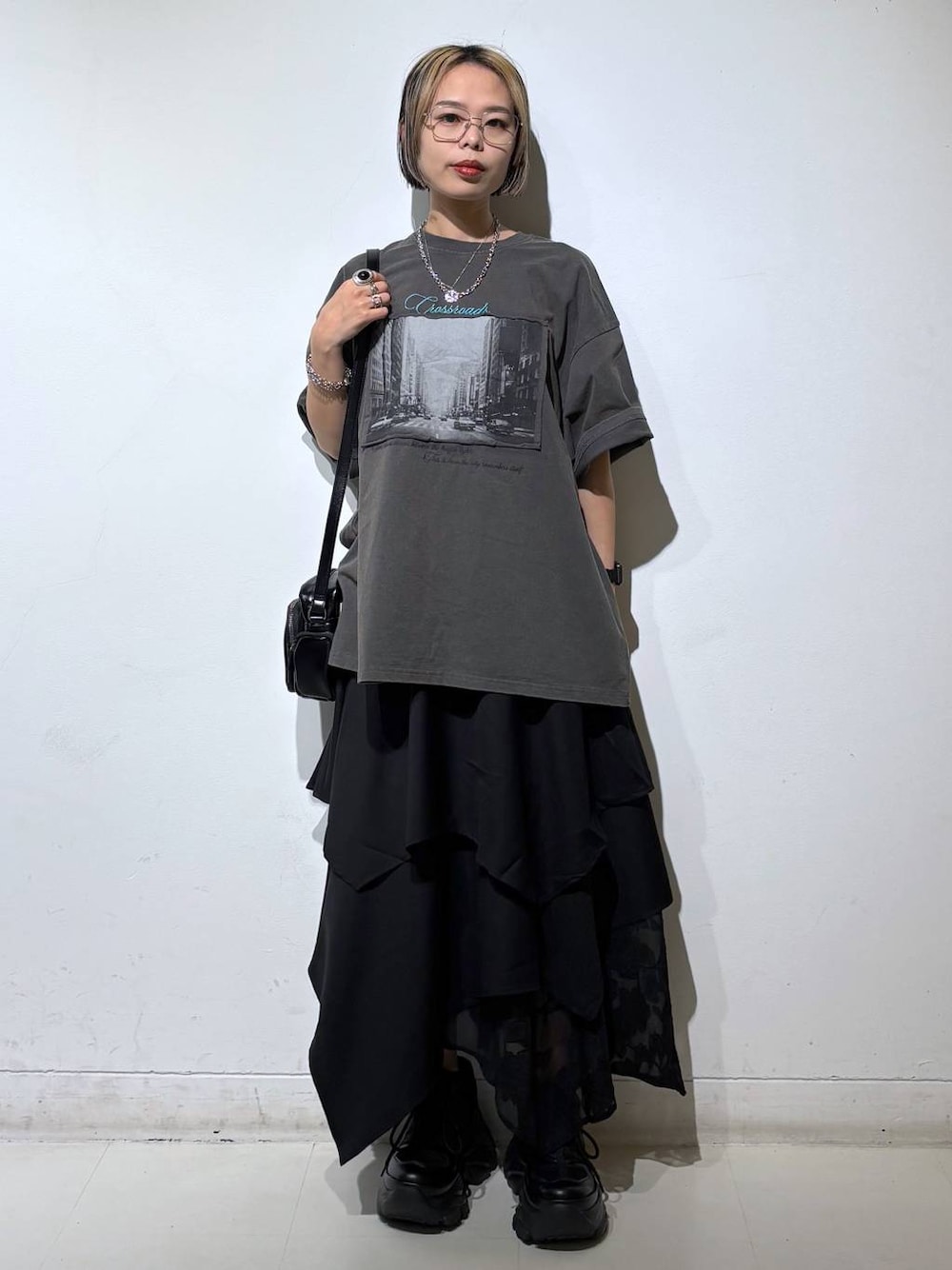 ブラック系のスニーカー、ブラック系のショルダーバッグ、グレー系のTシャツ/カットソーを着用したレディースの夏コーディネートの1枚目の写真