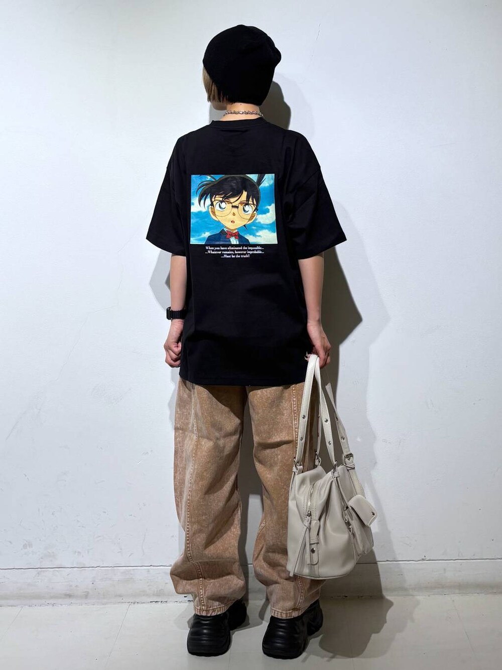 ブラック系のスニーカー、ブラウン系のデニムパンツ、ホワイト系のボストンバッグを着用したレディースの春コーディネートの1枚目の写真