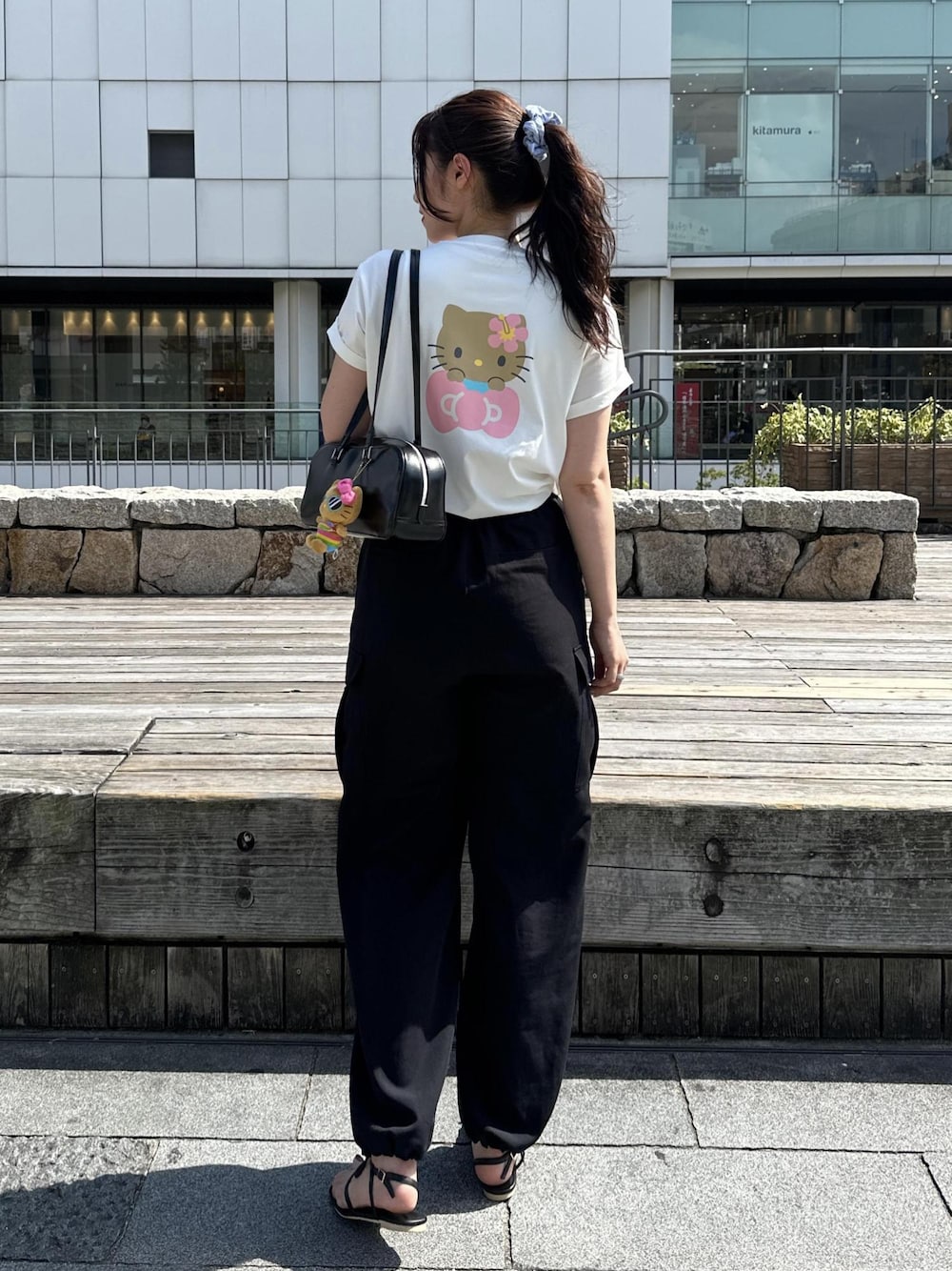 ブラック系のカーゴパンツ、ブラック系のサンダル、ホワイト系のTシャツ/カットソーを着用したレディースの夏コーディネートの1枚目の写真