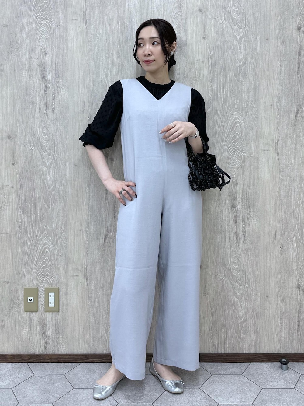 シルバー系のバレエシューズ、ブラック系のハンドバッグ、グレー系のつなぎ/オールインワンを着用したレディースの春コーディネートの1枚目の写真