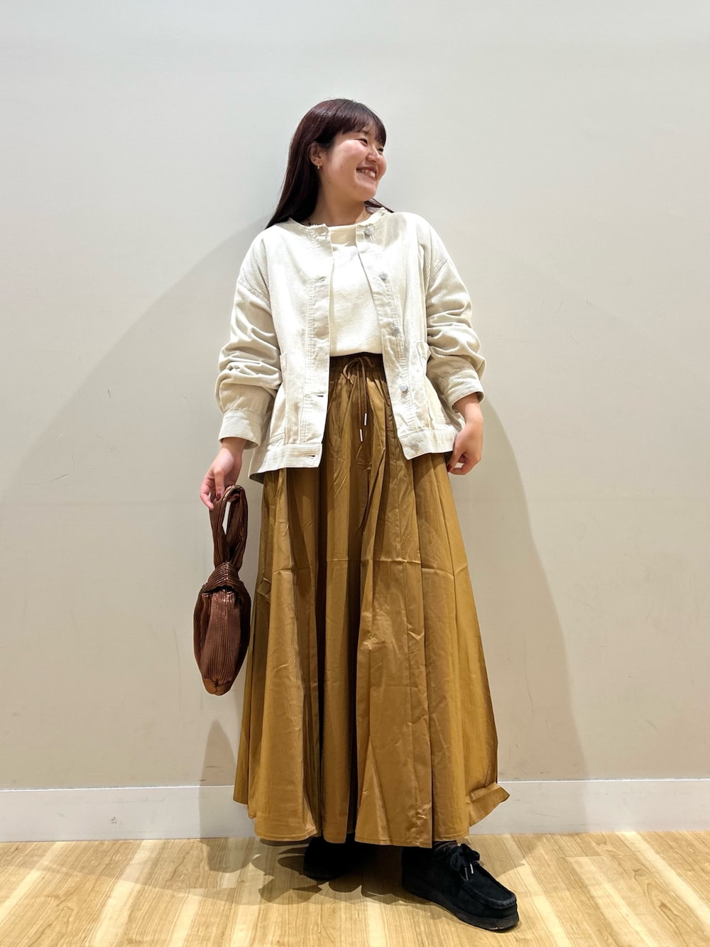 ホワイト系のノーカラージャケット、ホワイト系のTシャツ/カットソー、イエロー系のスカートを着用したレディースの秋コーディネートの1枚目の写真