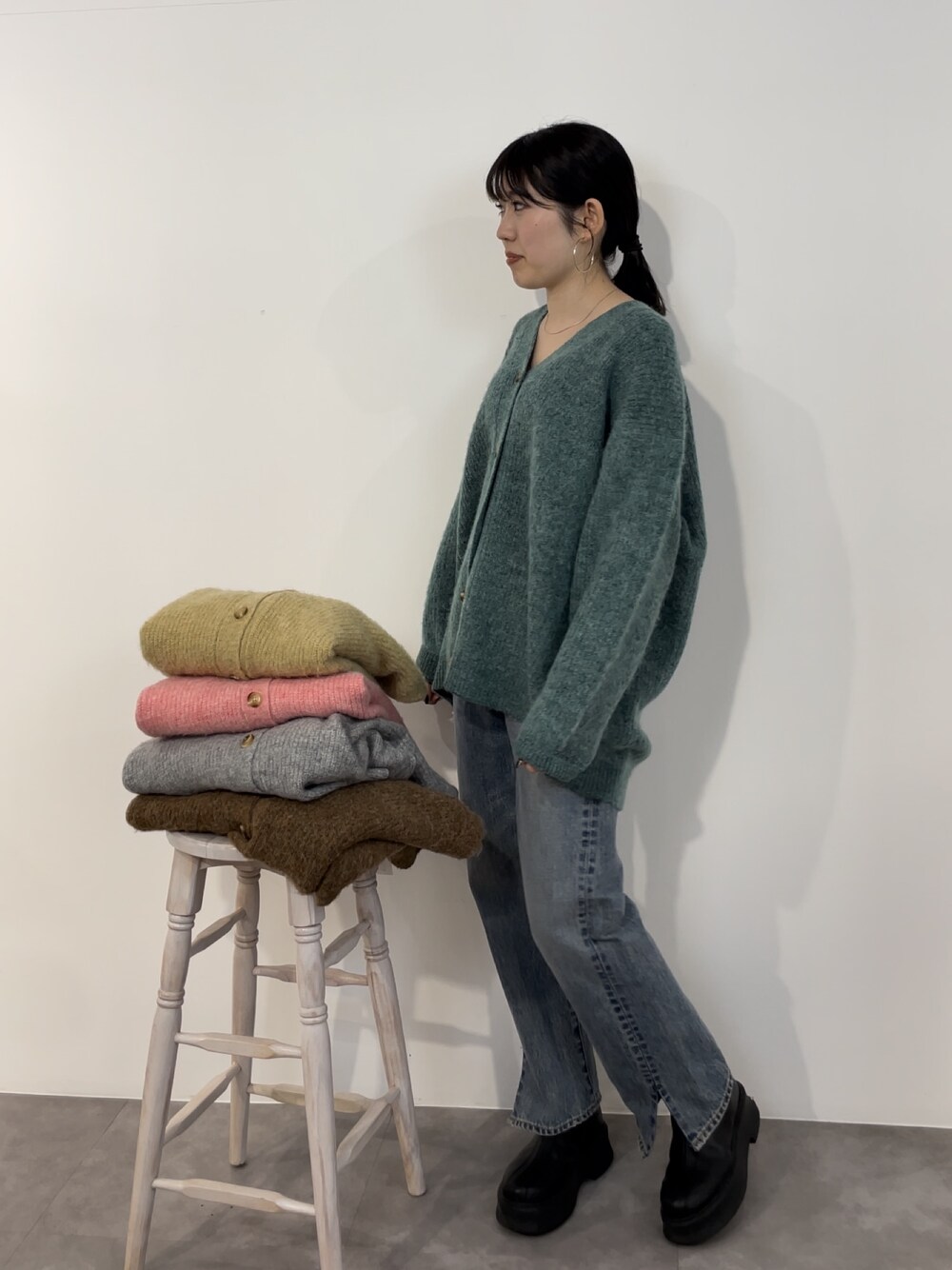 ブルー系のデニムパンツ、ブラック系のブーツ、グリーン系のカーディガン/ボレロを着用したレディースの冬コーディネートの1枚目の写真