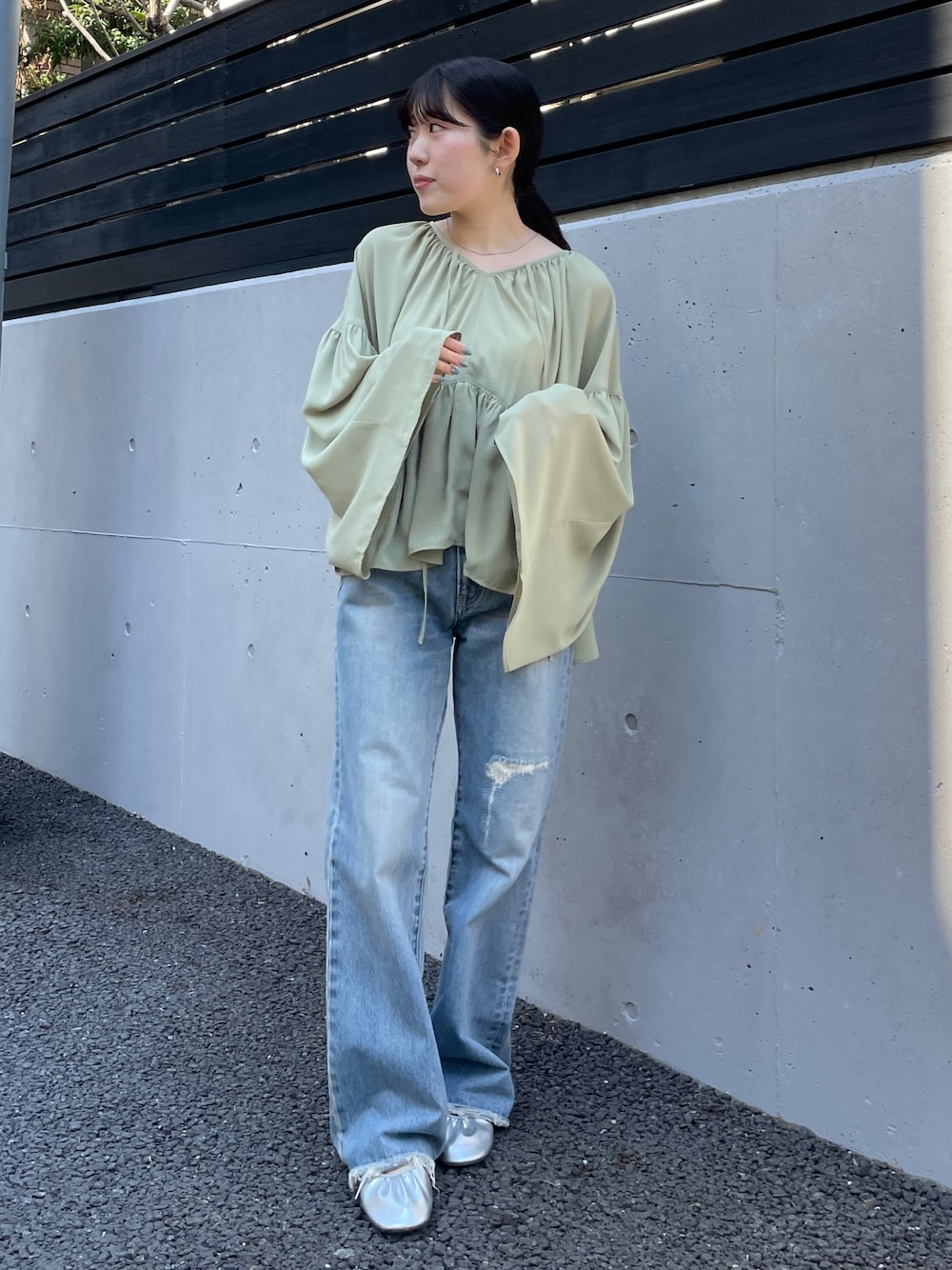 ブルー系のデニムパンツ、シルバー系のバレエシューズ、グリーン系のシャツ/ブラウスを着用したレディースの春コーディネートの1枚目の写真