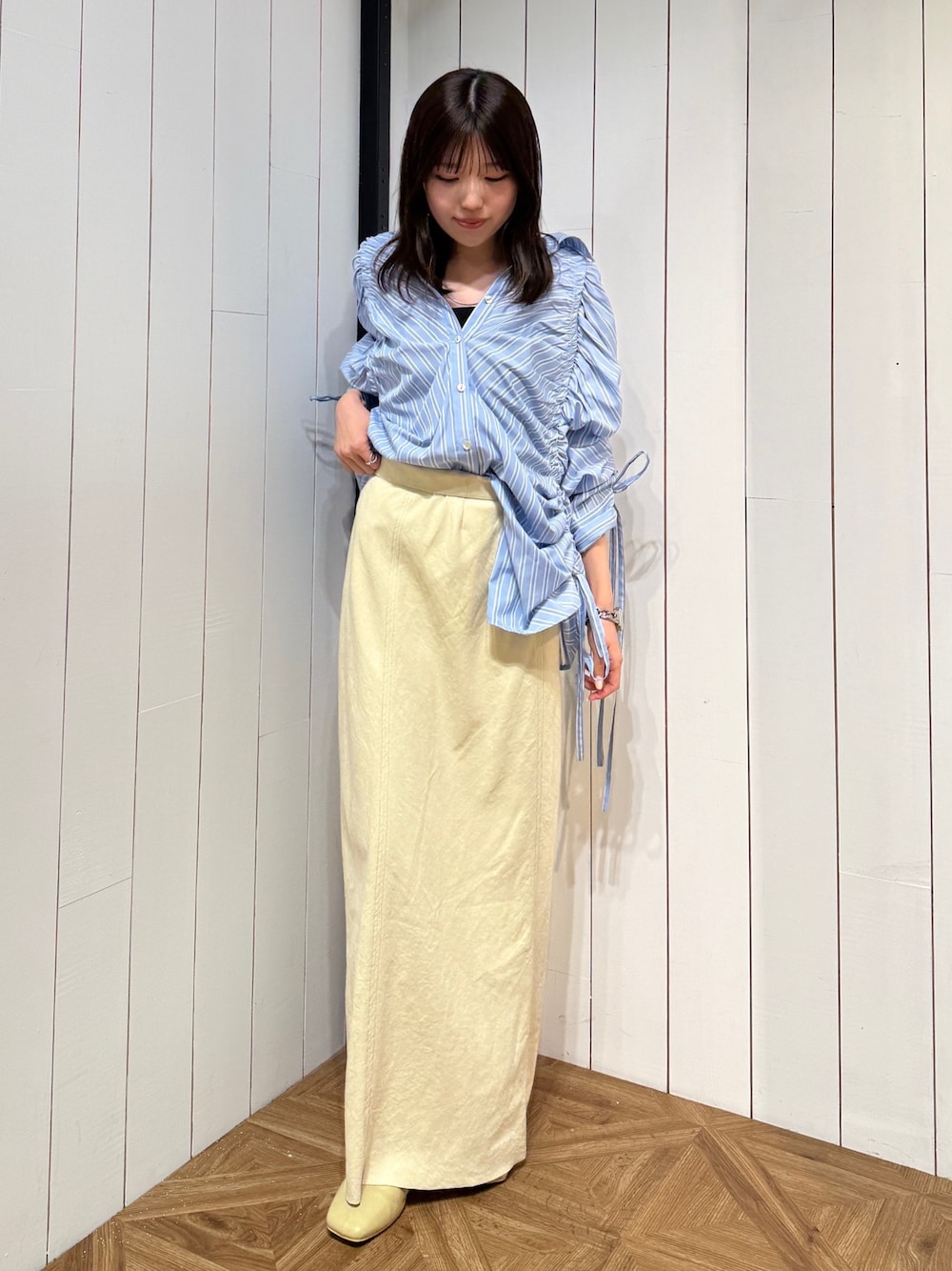 イエロー系のスカート、イエロー系のサンダル、ブルー系のシャツ/ブラウスを着用したレディースの春コーディネートの1枚目の写真