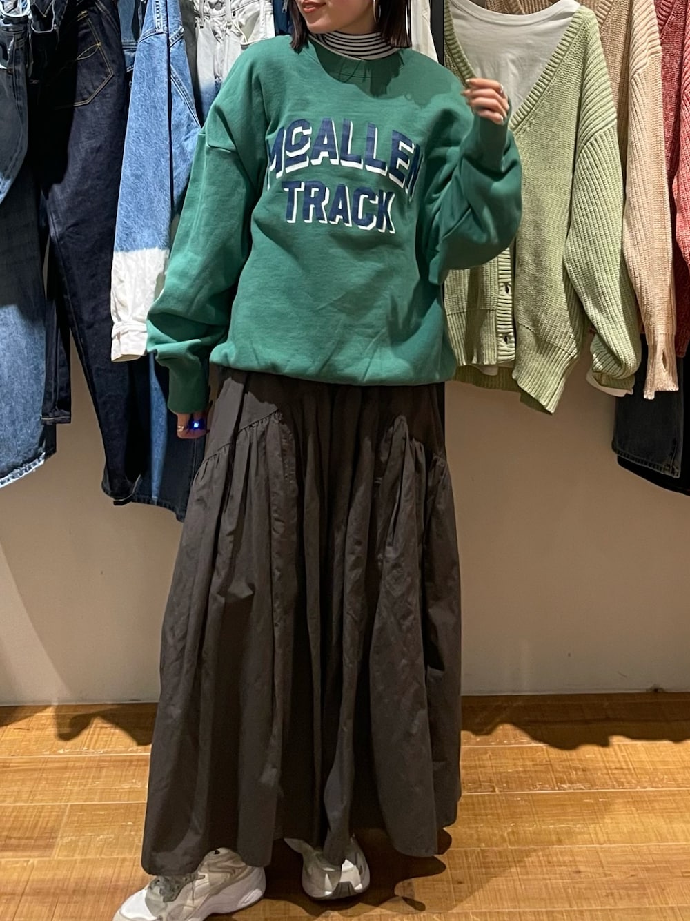 グレー系のスカート、グリーン系のスウェット、ホワイト系のニット/セーターを着用したレディースの冬コーディネートの1枚目の写真