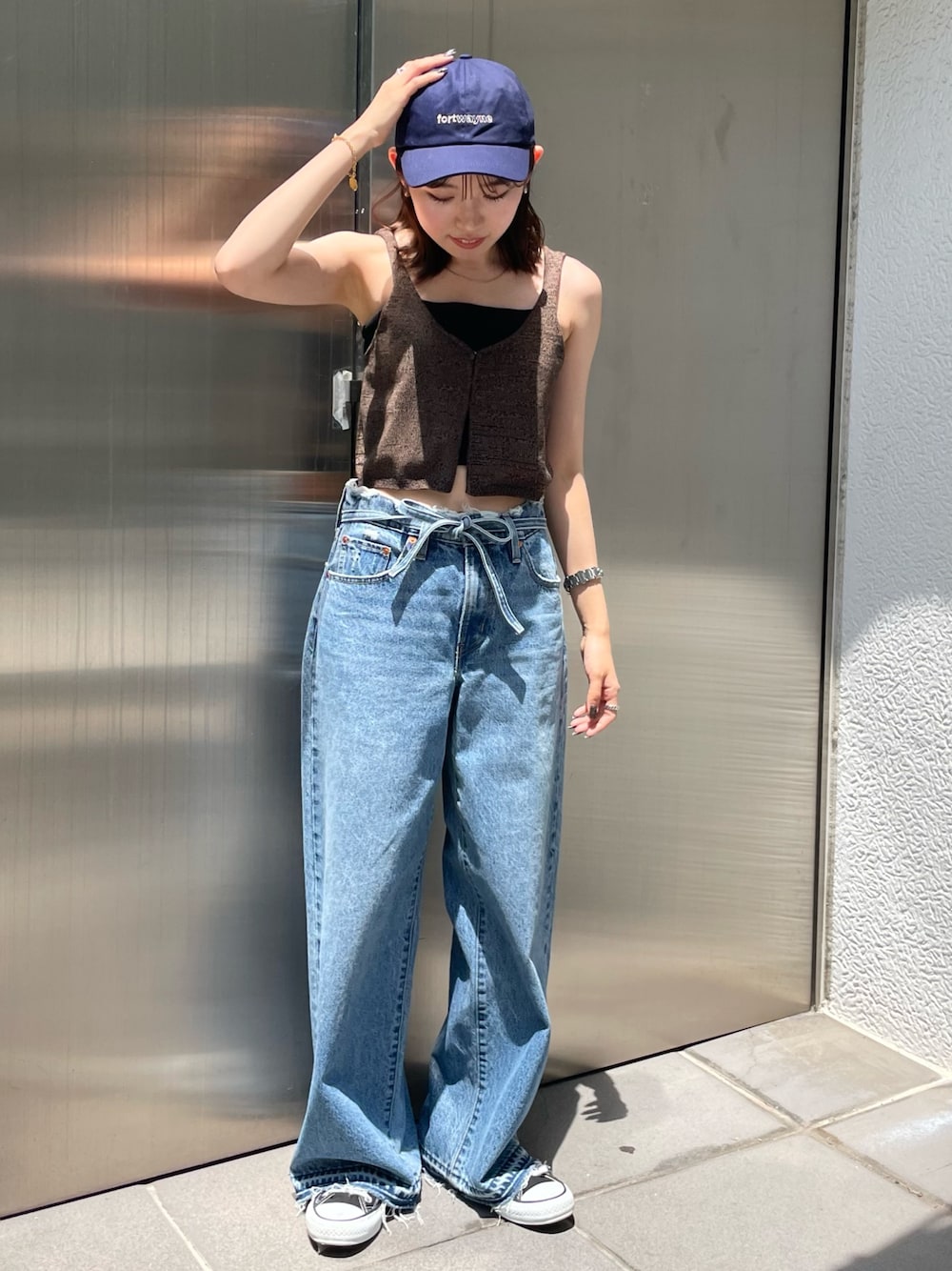 ブラウン系のベスト、ブルー系のデニムパンツ、ブルー系のキャップを着用したレディースの夏コーディネートの1枚目の写真