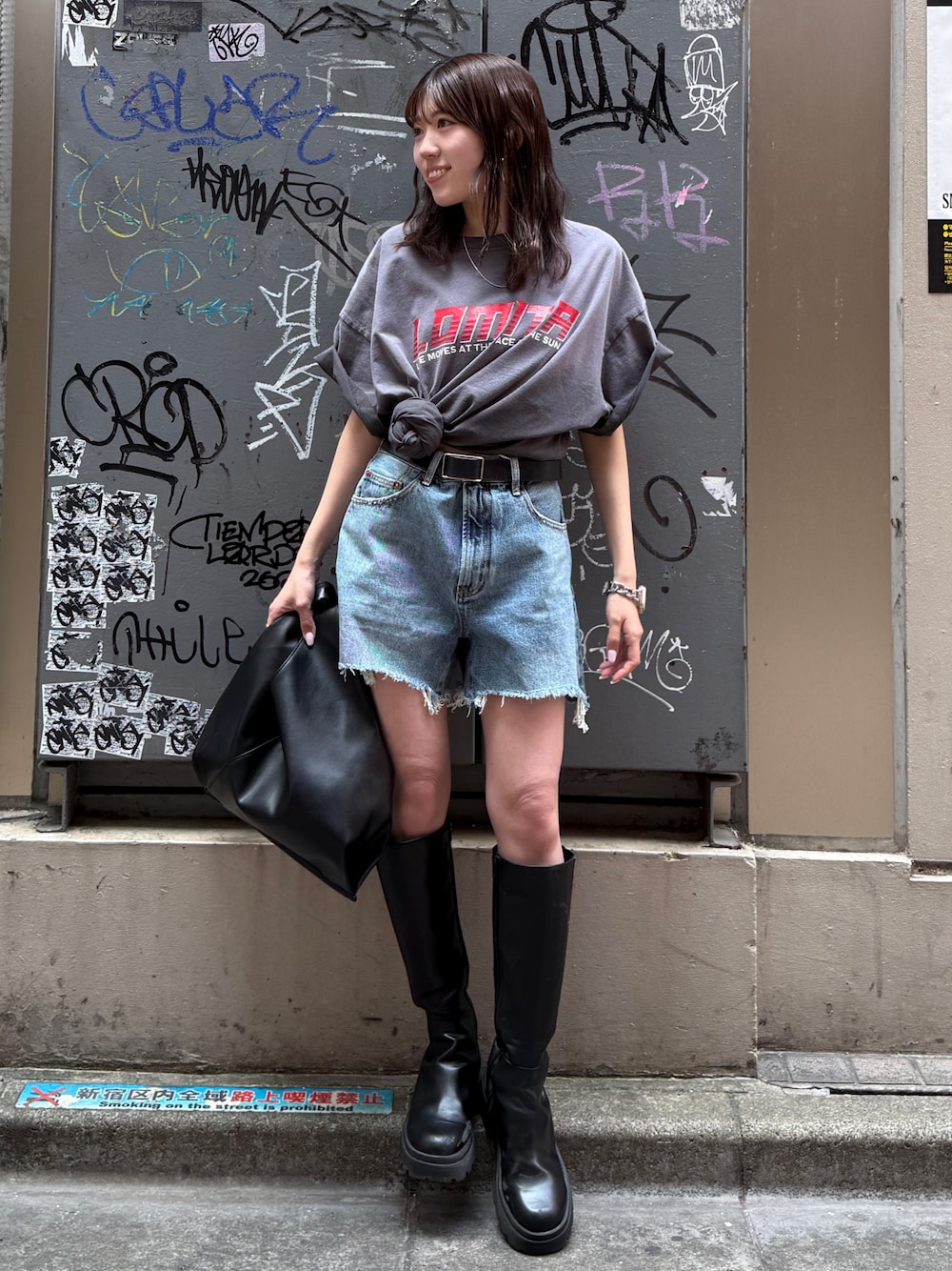 ブルー系のデニムパンツ、グレー系のTシャツ/カットソー、ブラック系のハンドバッグを着用したレディースの春コーディネートの1枚目の写真