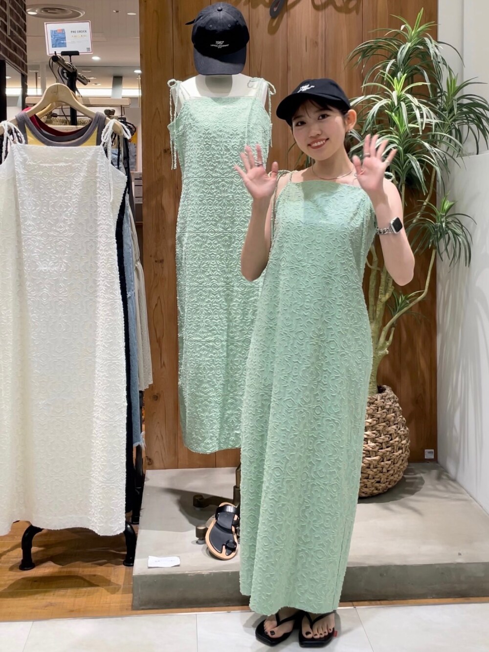 ブラック系のサンダル、グリーン系のワンピース、ブラック系のキャップを着用したレディースの夏コーディネートの1枚目の写真
