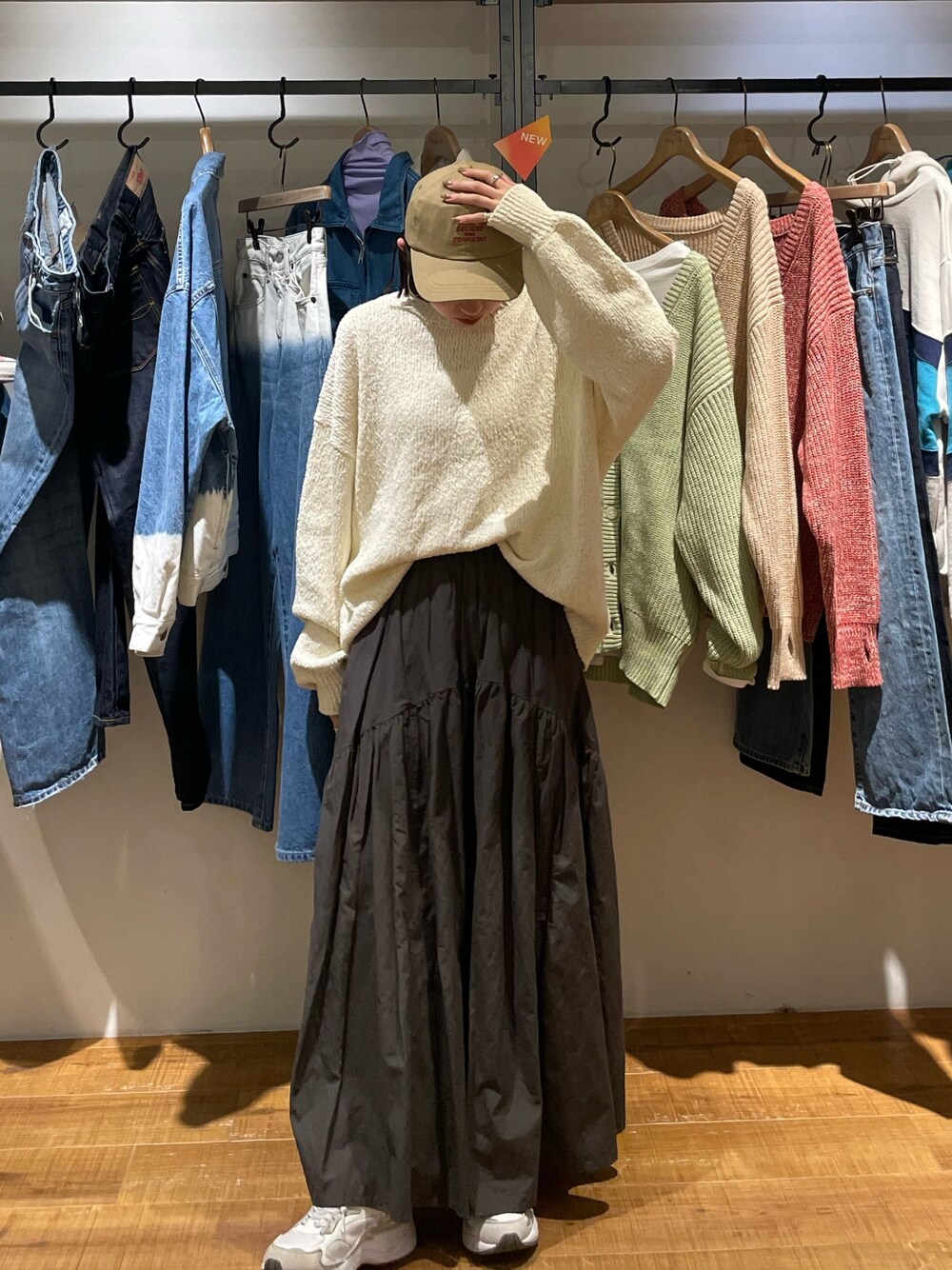 グレー系のスカート、ホワイト系のニット/セーター、ベージュ系のキャップを着用したレディースの冬コーディネートの1枚目の写真