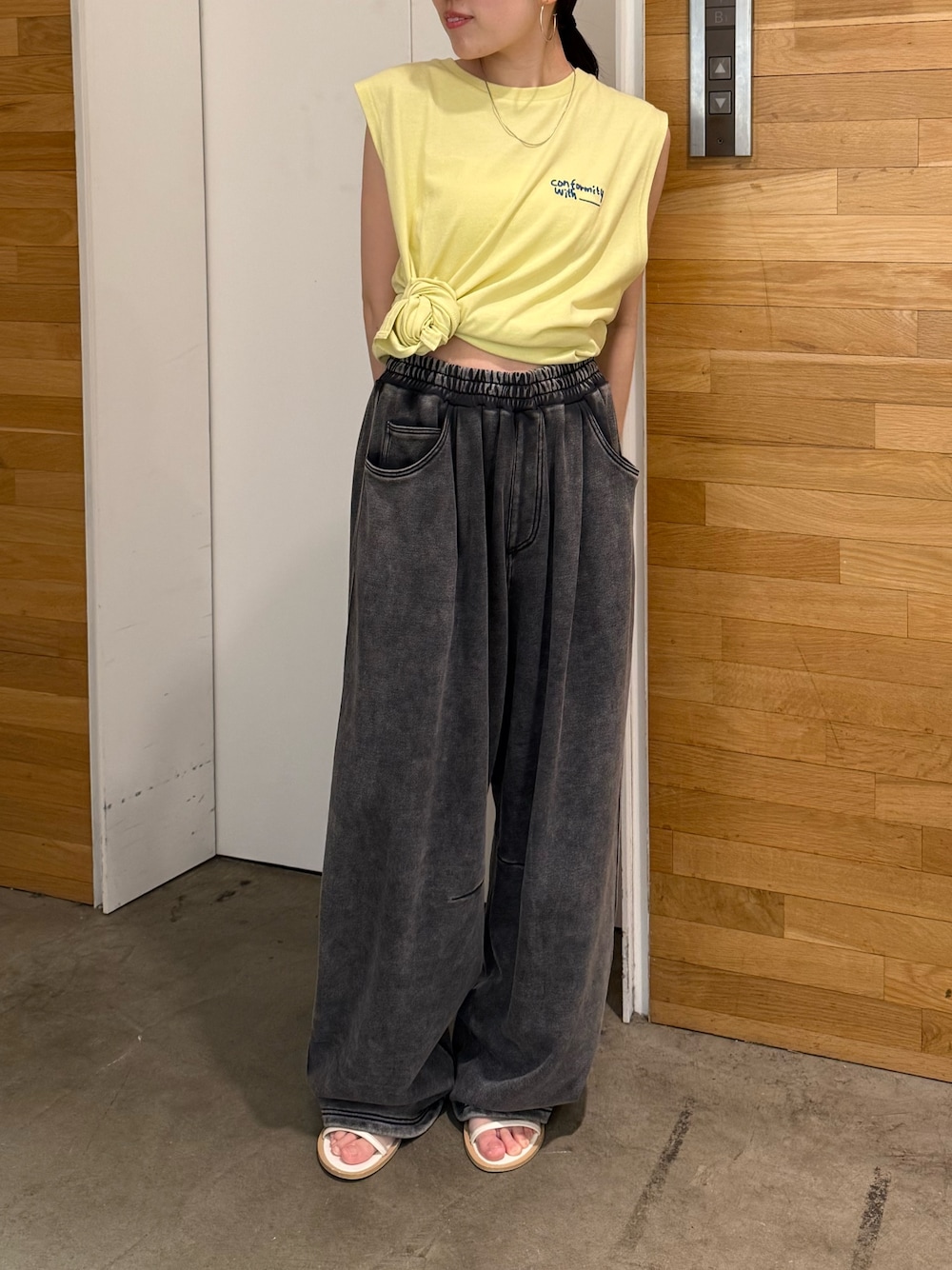 グレー系のスウェットパンツ、イエロー系のタンクトップ、ホワイト系のサンダルを着用したレディースの夏コーディネートの1枚目の写真