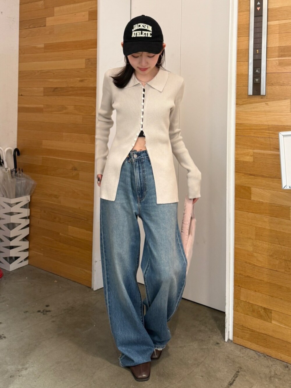 ブラウン系のブーツ、ブルー系のデニムパンツ、ピンク系のハンドバッグを着用したレディースの秋コーディネートの1枚目の写真