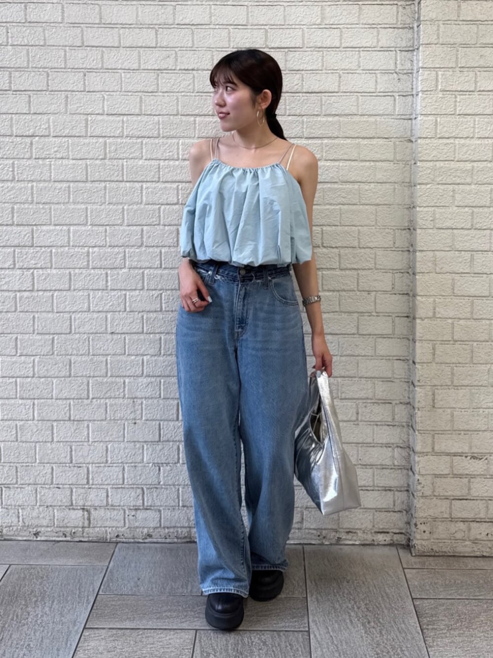 シルバー系のハンドバッグ、ブルー系のデニムパンツ、ブルー系のキャミソールを着用したレディースの夏コーディネートの1枚目の写真