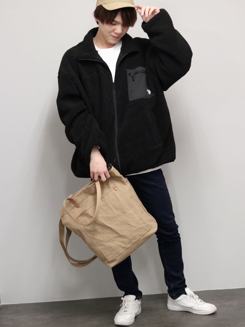 ベージュ系のトートバッグ、ブラック系のブルゾン、ホワイト系のスニーカーを着用したメンズの冬コーディネートの1枚目の写真