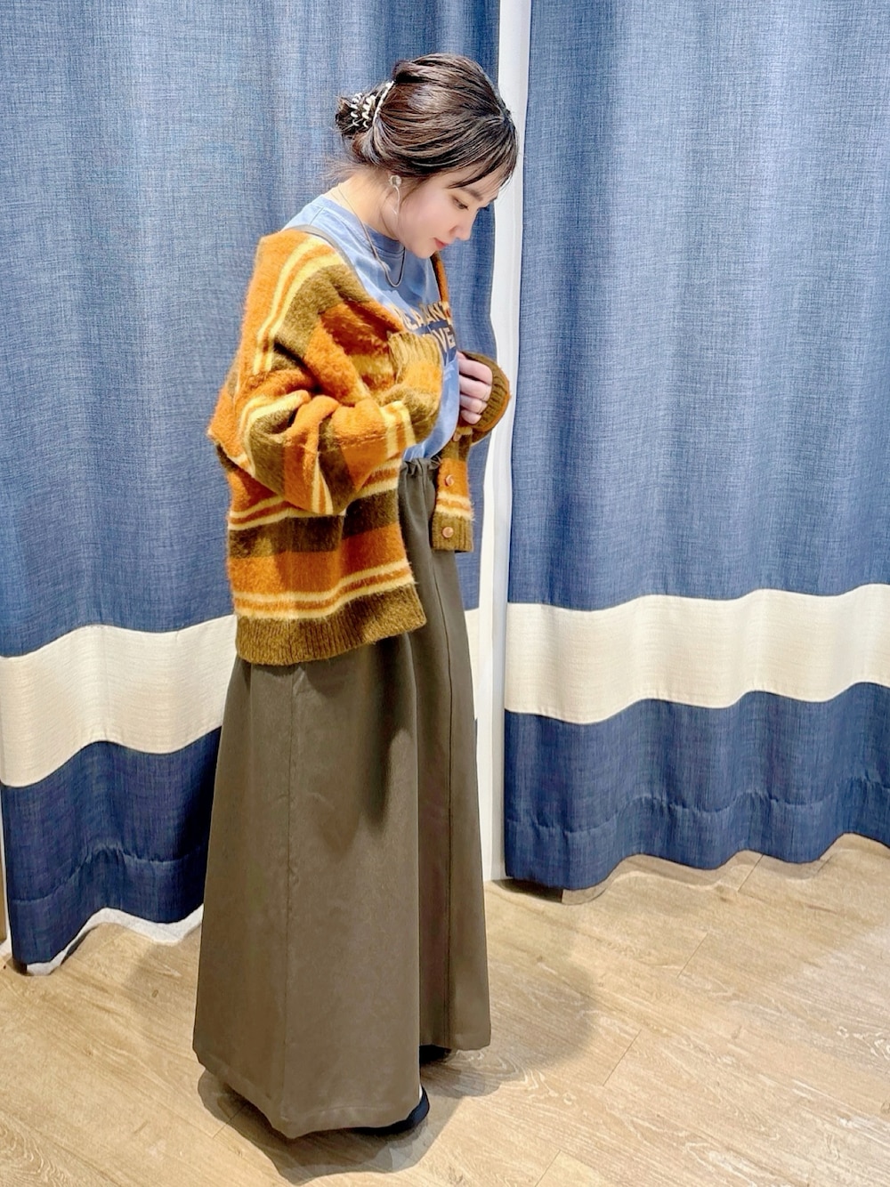 オレンジ系のカーディガン/ボレロ、グレー系のワンピース、ブルー系のTシャツ/カットソーを着用したレディースの冬コーディネートの1枚目の写真
