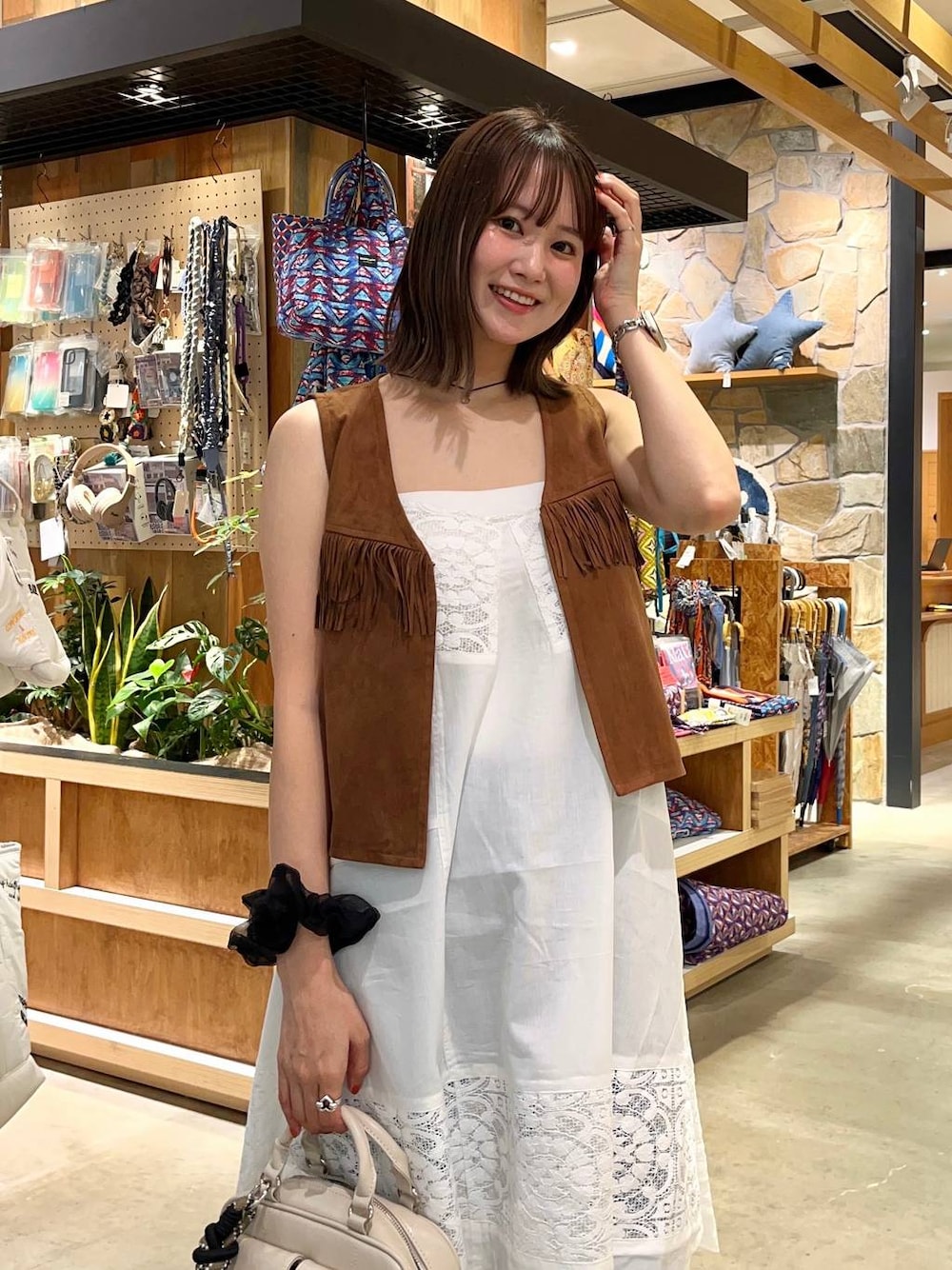 ブラウン系のサンダル、ホワイト系のボストンバッグ、ブルー系のデニムパンツを着用したレディースの夏コーディネートの1枚目の写真