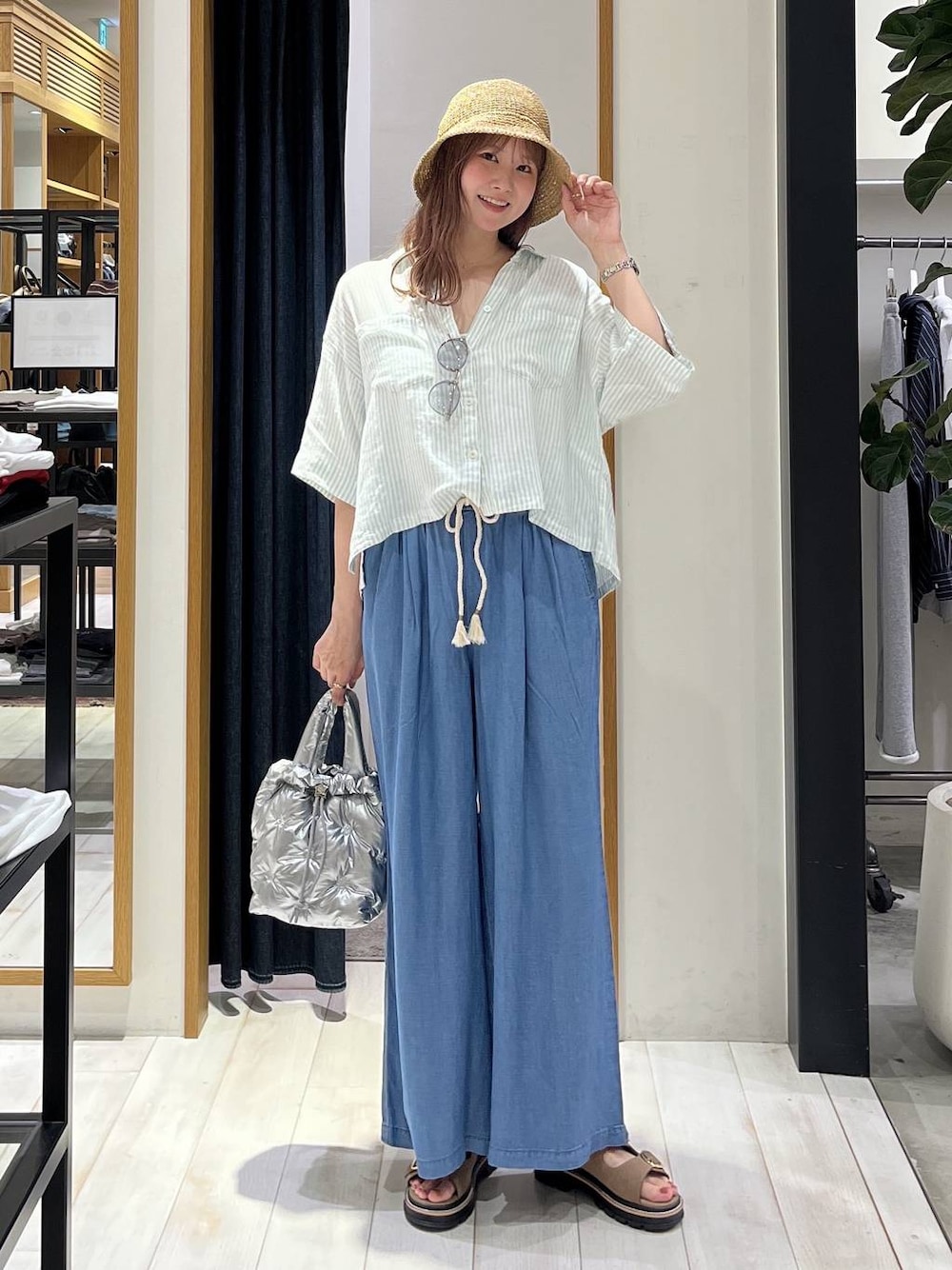 ブルー系のデニムパンツ、シルバー系のショルダーバッグ、ベージュ系のサンダルを着用したレディースの春コーディネートの1枚目の写真