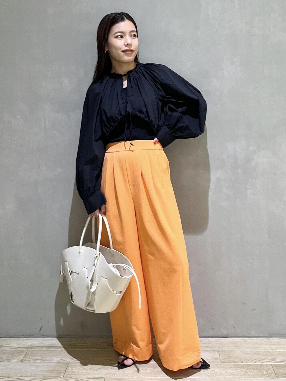 ブラック系のサンダル、ホワイト系のトートバッグ、オレンジ系のその他パンツを着用したレディースの春コーディネートの1枚目の写真