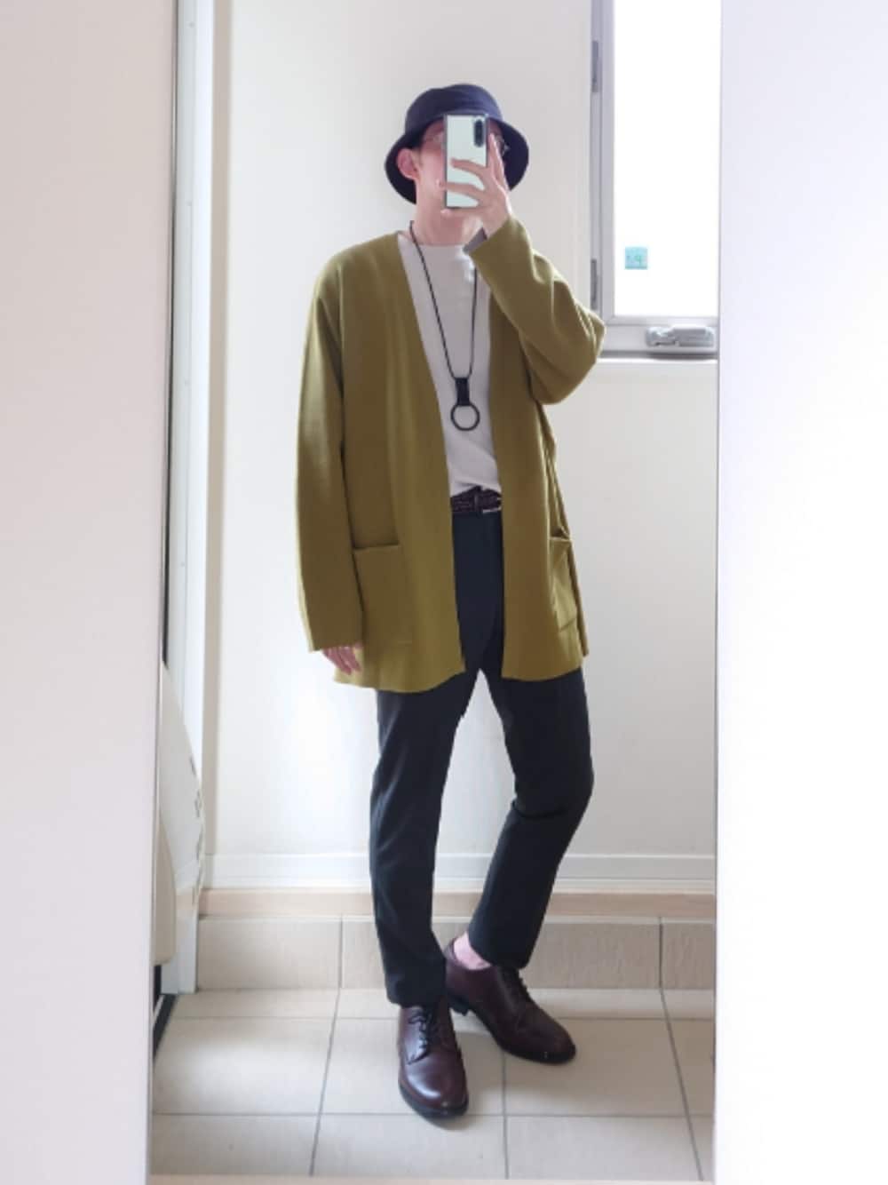 グリーン系のカーディガン/ボレロ、ブラック系のスラックス、ブラウン系のドレスシューズを着用したメンズの冬コーディネートの1枚目の写真