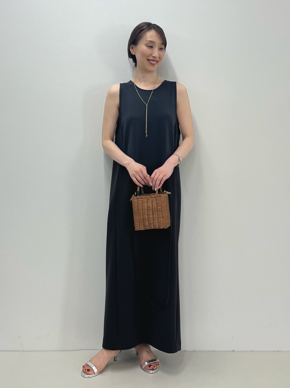 グレー系のワンピース、イエロー系のかごバッグ、シルバー系のサンダルを着用したレディースの春コーディネートの1枚目の写真