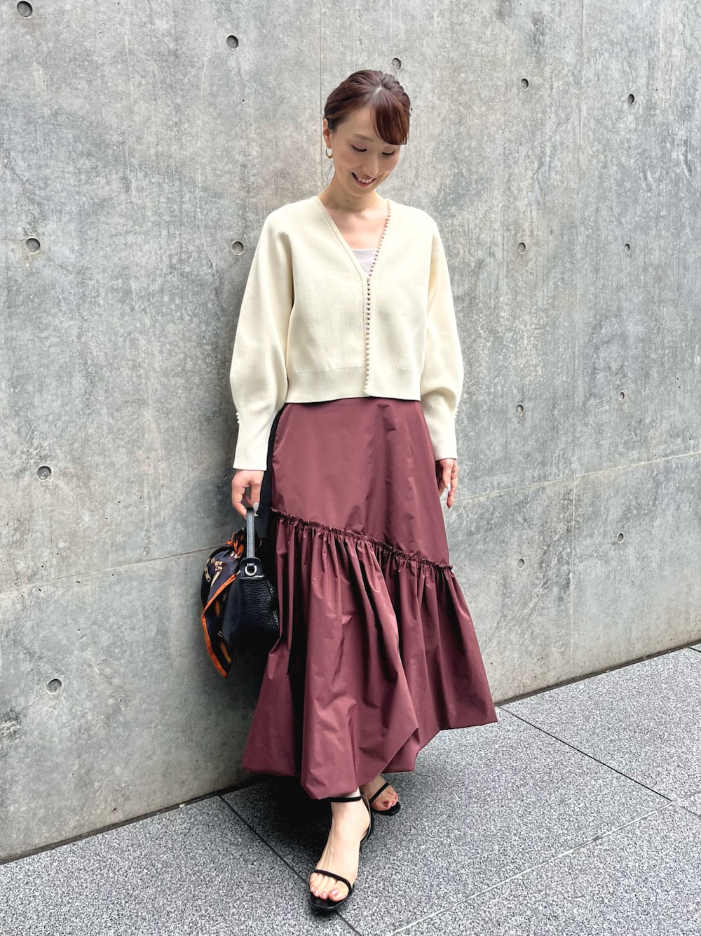 ホワイト系のカーディガン/ボレロ、レッド系のスカート、ブラック系のショルダーバッグを着用したレディースの夏コーディネートの1枚目の写真