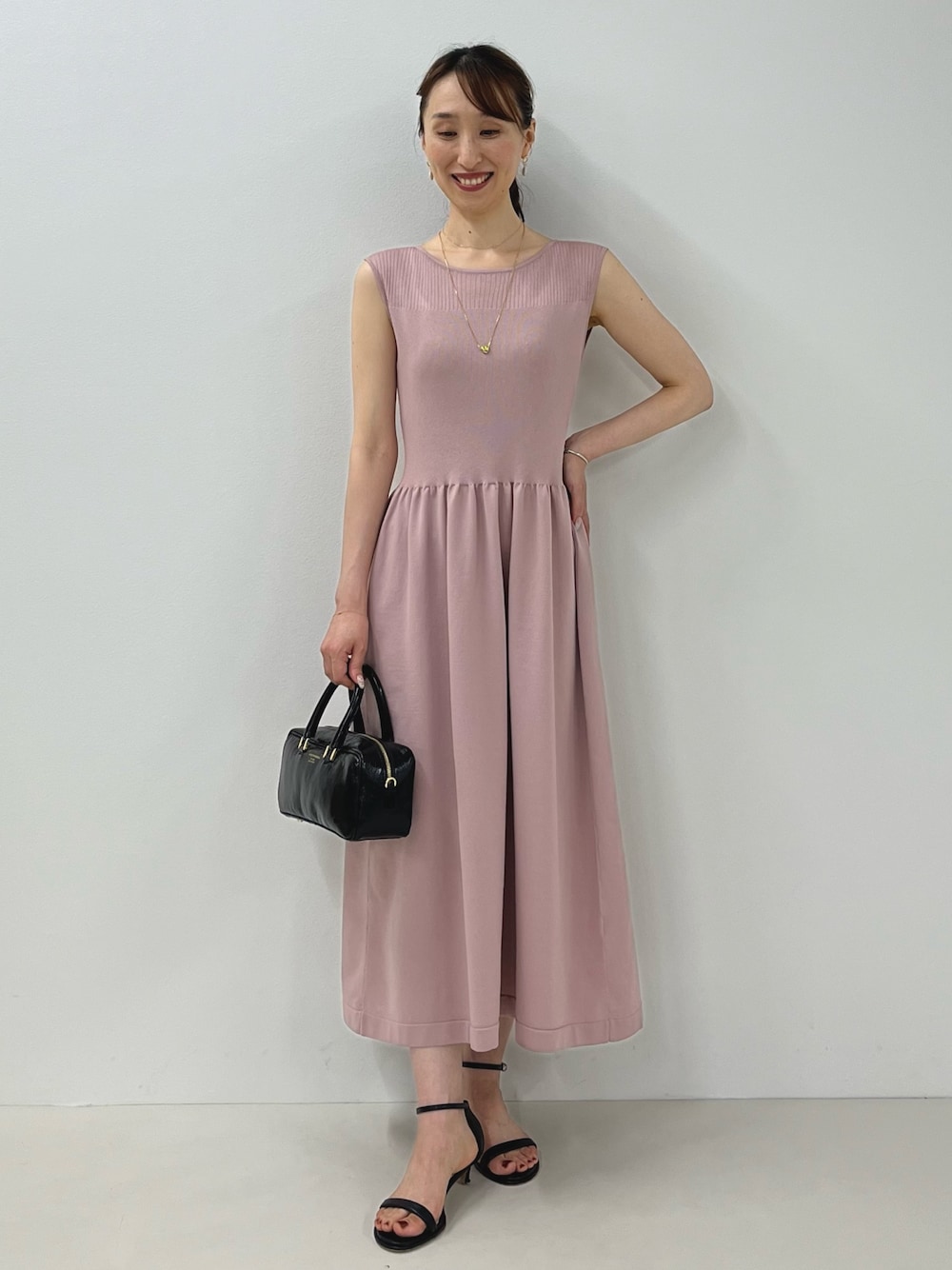 ピンク系のワンピース、ブラック系のサンダル、ゴールド系のピアス（両耳用）を着用したレディースの夏コーディネートの1枚目の写真