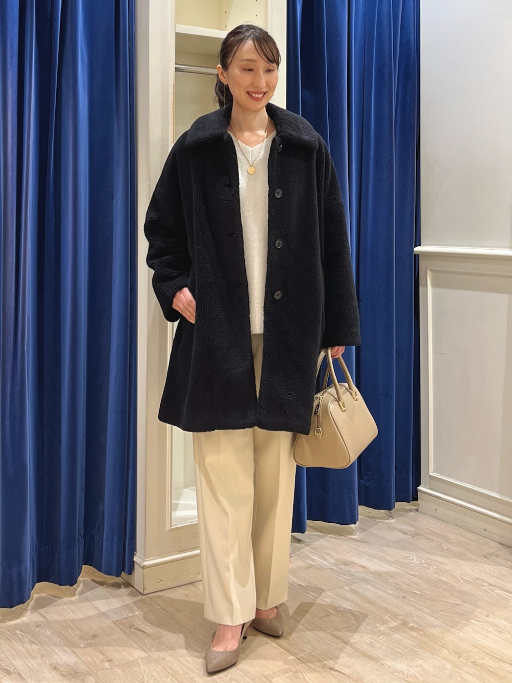 ブラック系のダッフルコート、ホワイト系のニット/セーター、イエロー系のその他パンツを着用したレディースの冬コーディネートの1枚目の写真