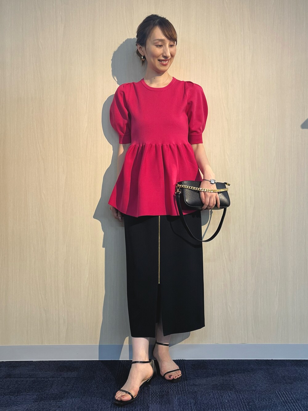 ピンク系のニット/セーター、ブラック系のショルダーバッグ、ブラック系のスカートを着用したレディースの夏コーディネートの1枚目の写真
