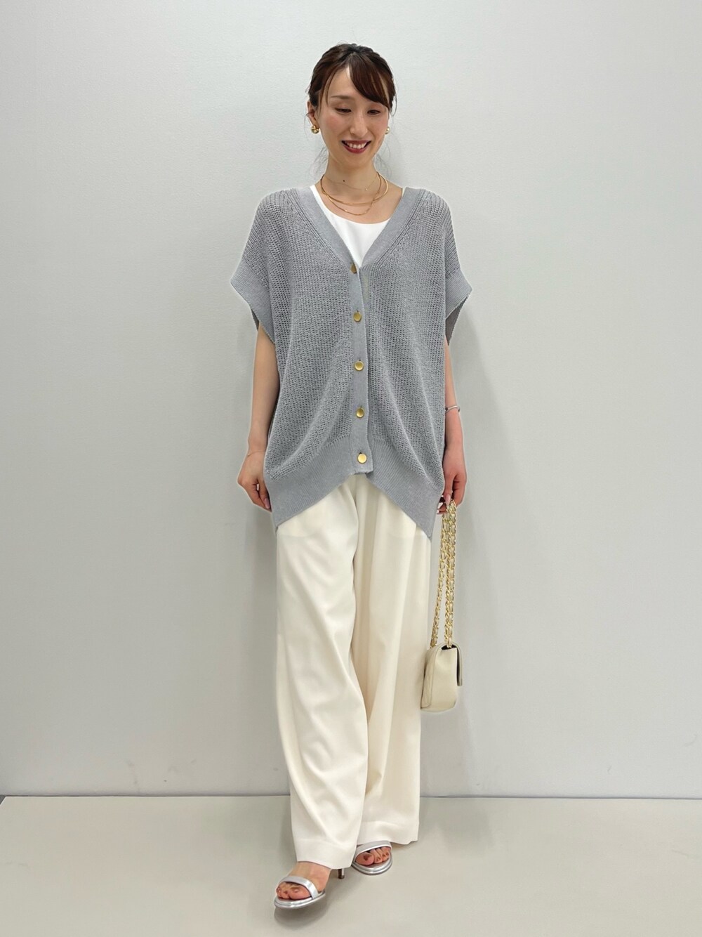 グレー系のベスト、ホワイト系のタンクトップ、ホワイト系のその他パンツを着用したレディースの春コーディネートの1枚目の写真