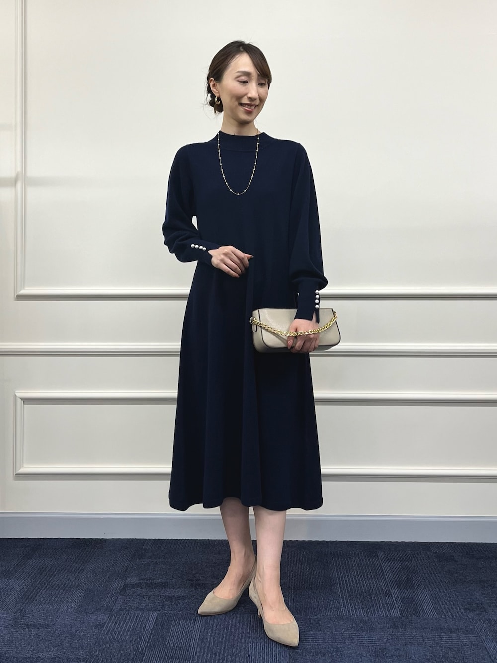 ベージュ系のショルダーバッグ、ブルー系のワンピース、ゴールド系のネックレスを着用したレディースの冬コーディネートの1枚目の写真