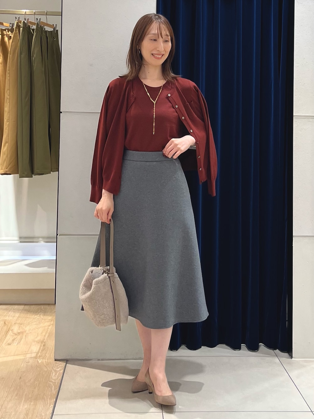 レッド系のニット/セーター、レッド系のカーディガン/ボレロ、グレー系のスカートを着用したレディースの秋コーディネートの1枚目の写真