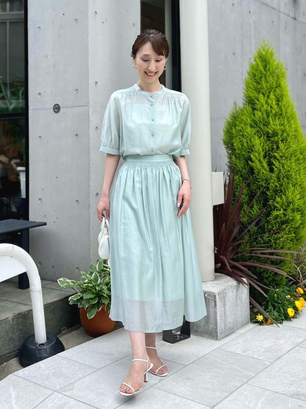 グリーン系のシャツ/ブラウス、グリーン系のスカート、ホワイト系のボストンバッグを着用したレディースの春コーディネートの1枚目の写真
