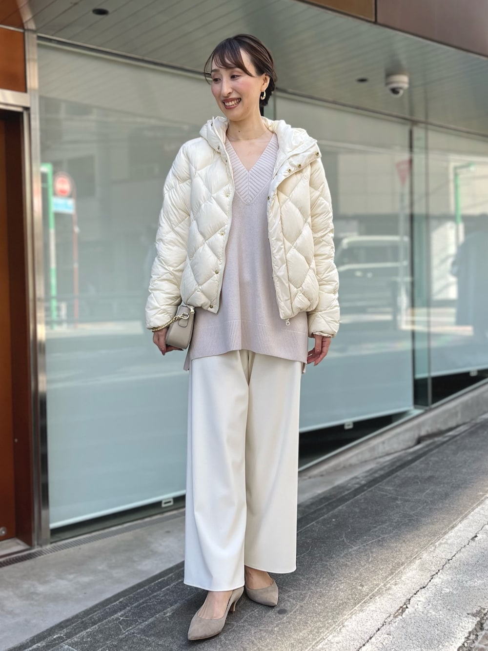 ホワイト系のダウンジャケット/コート、ベージュ系のニット/セーター、ベージュ系のショルダーバッグを着用したレディースの秋コーディネートの1枚目の写真