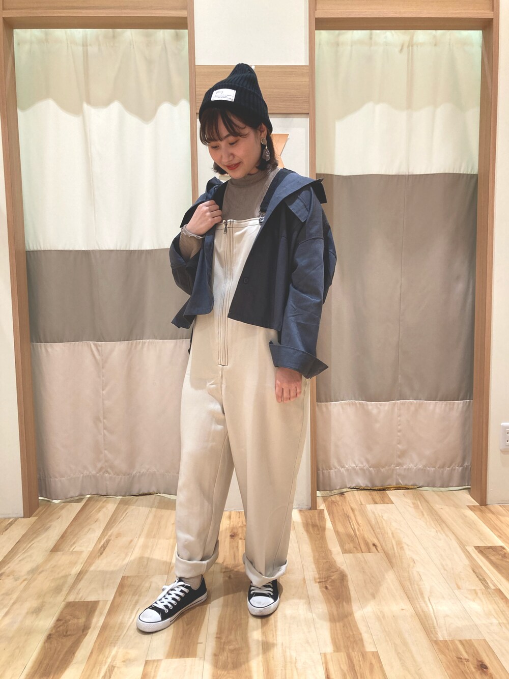 ベージュ系のサロペット/オーバーオール、ブラック系のニットキャップ/ビーニーを着用したレディースの秋コーディネートの1枚目の写真