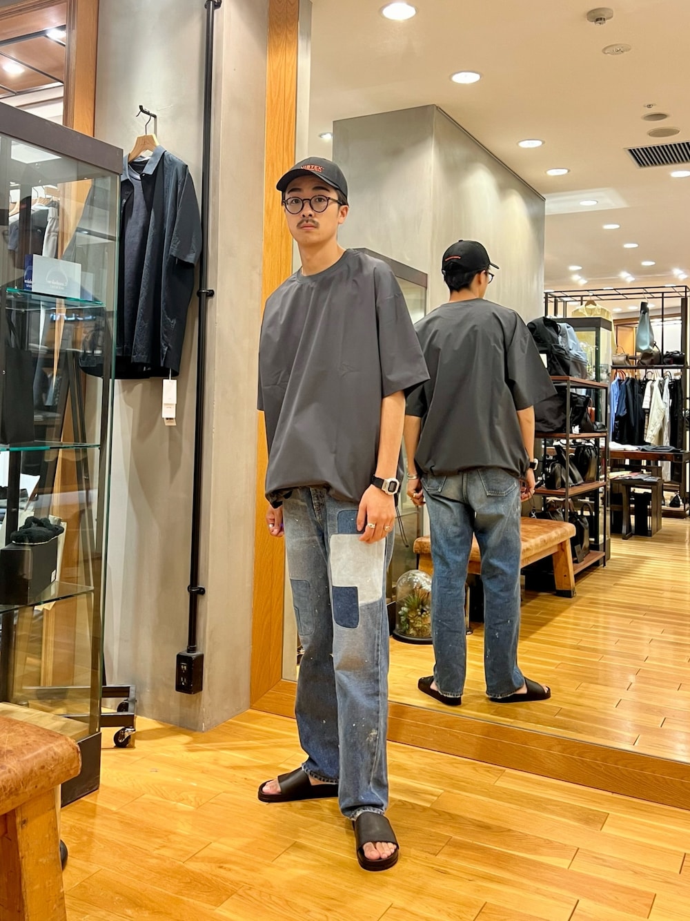 グレー系のTシャツ/カットソー、ブルー系のデニムパンツ、ブラック系のキャップを着用したメンズの夏コーディネートの1枚目の写真