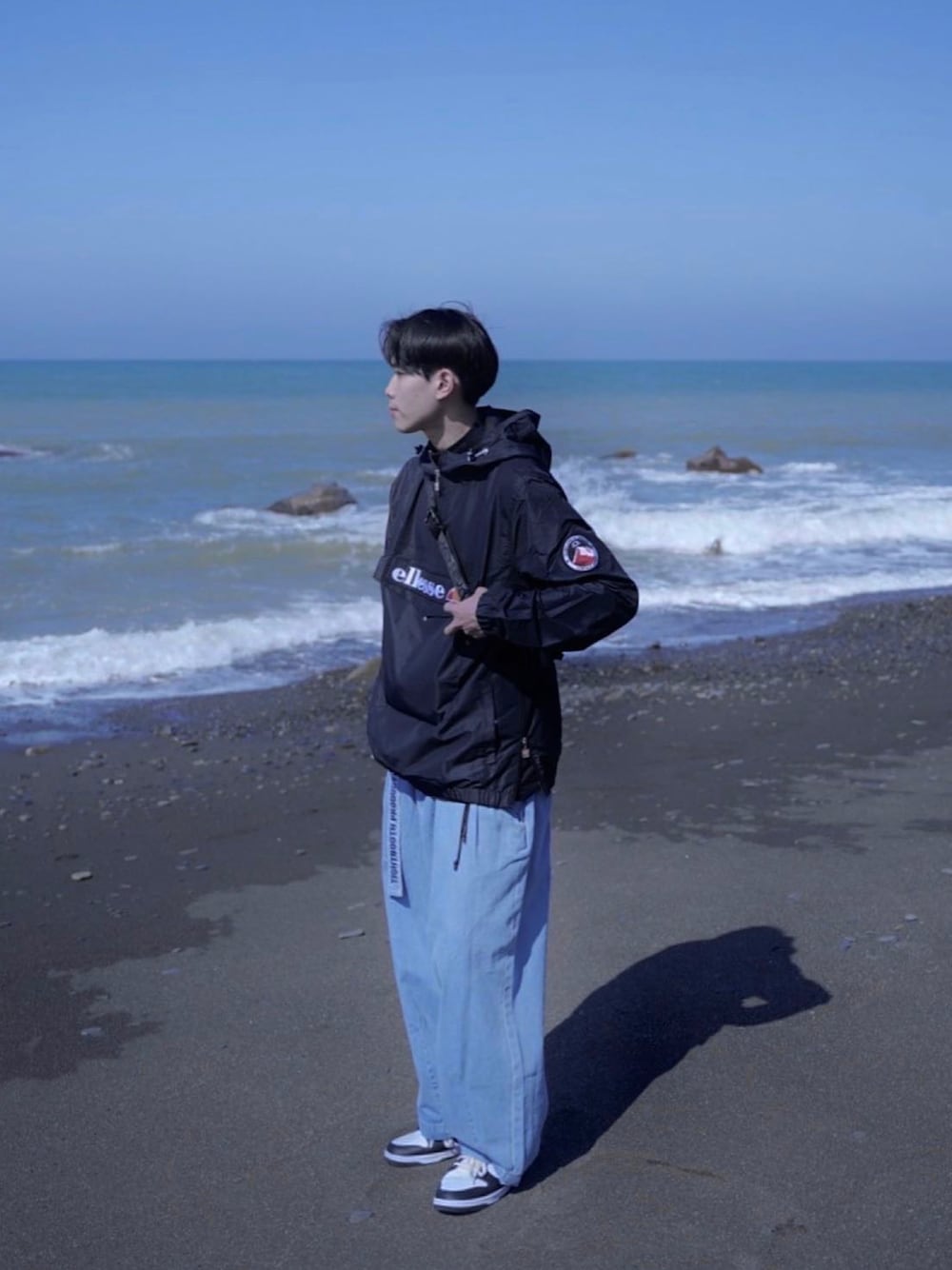 ブラック系のマウンテンパーカー、ブルー系のデニムパンツ、ブラック系のスニーカーを着用したメンズの冬コーディネートの1枚目の写真