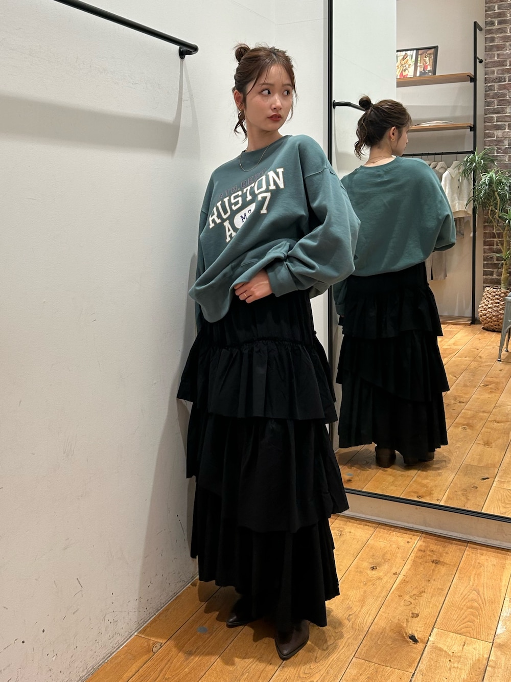 グリーン系のスウェット、ブラック系のスカートを着用したレディースの冬コーディネートの1枚目の写真