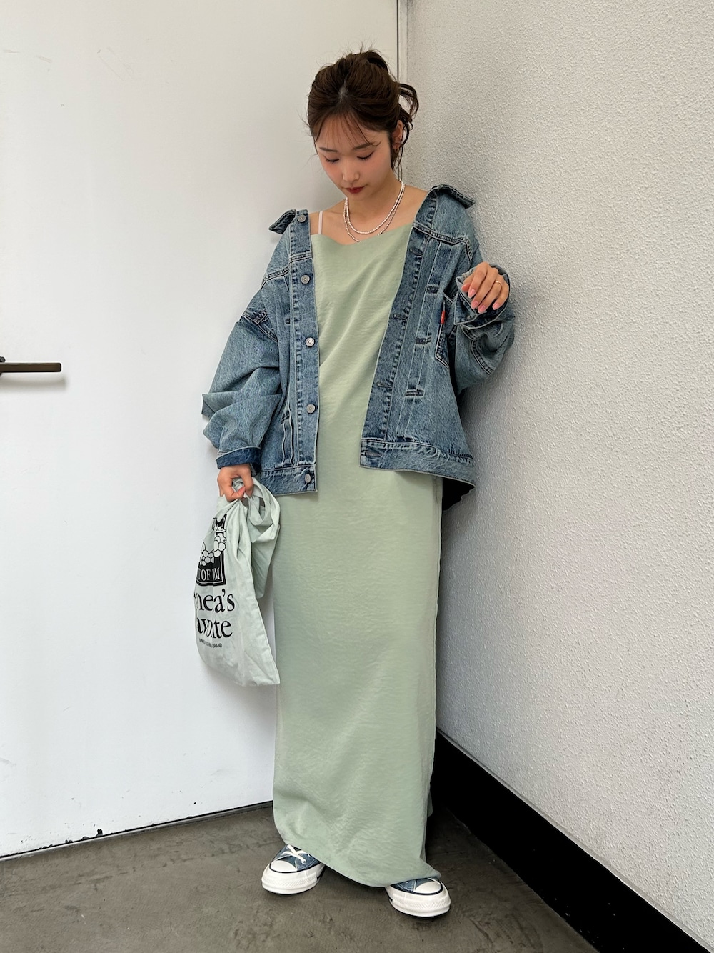 グリーン系のトートバッグ、ブルー系のスニーカー、ブルー系のデニムジャケットを着用したレディースの春コーディネートの1枚目の写真